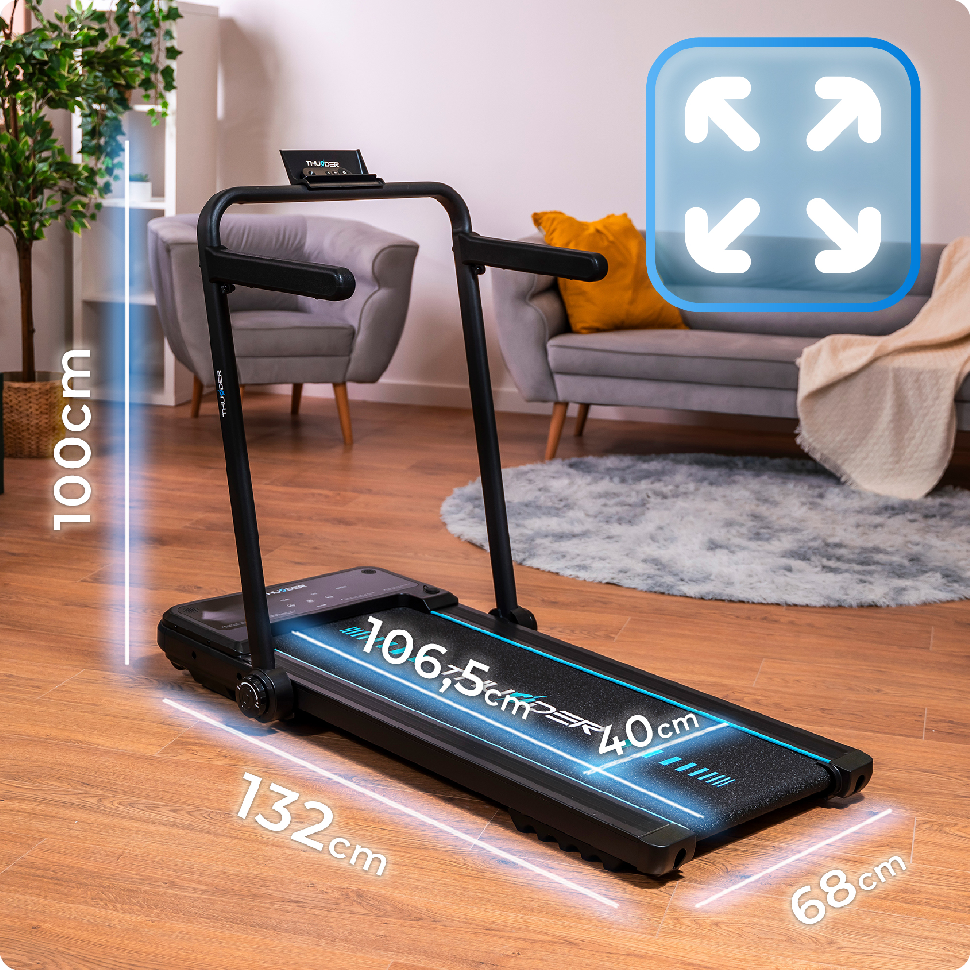 Czarna bieżnia na drewnianej podłodze. Wymiary są wskazane. Szara sofa w tle.