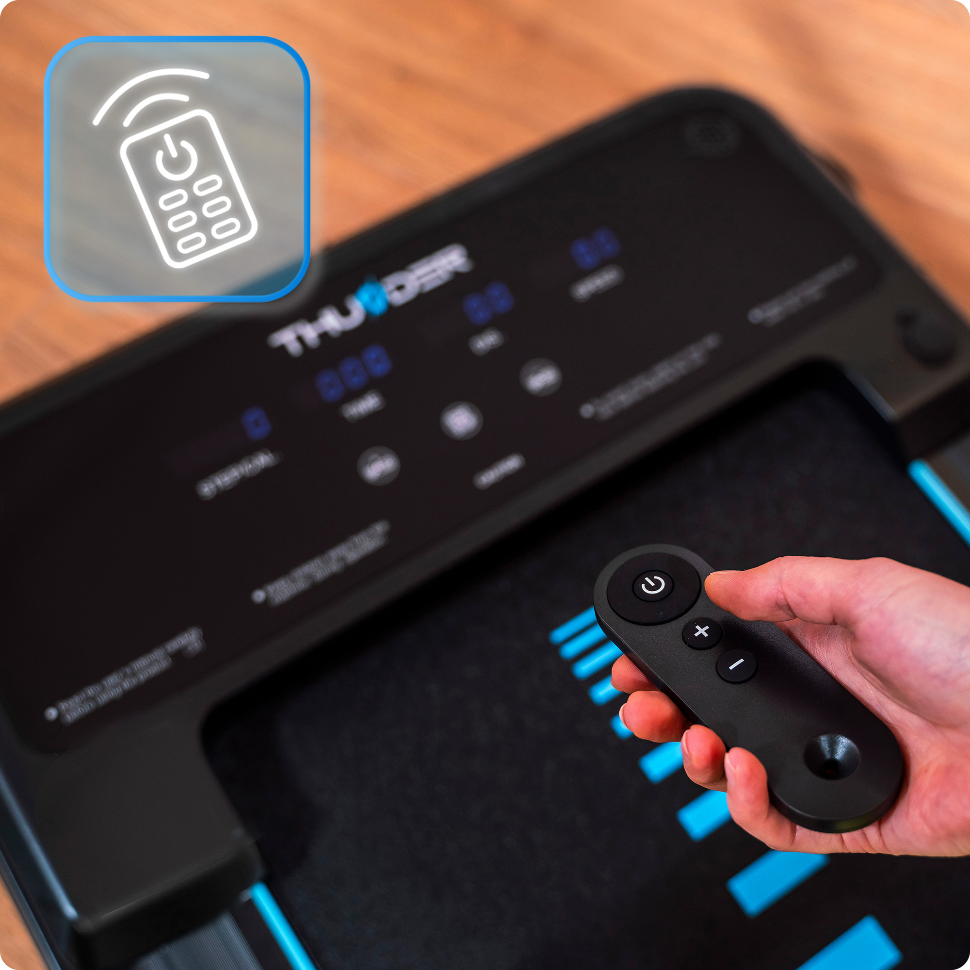 Dłoń trzymająca pilota do bieżni. Bieżnia jest czarna i ma ekran.