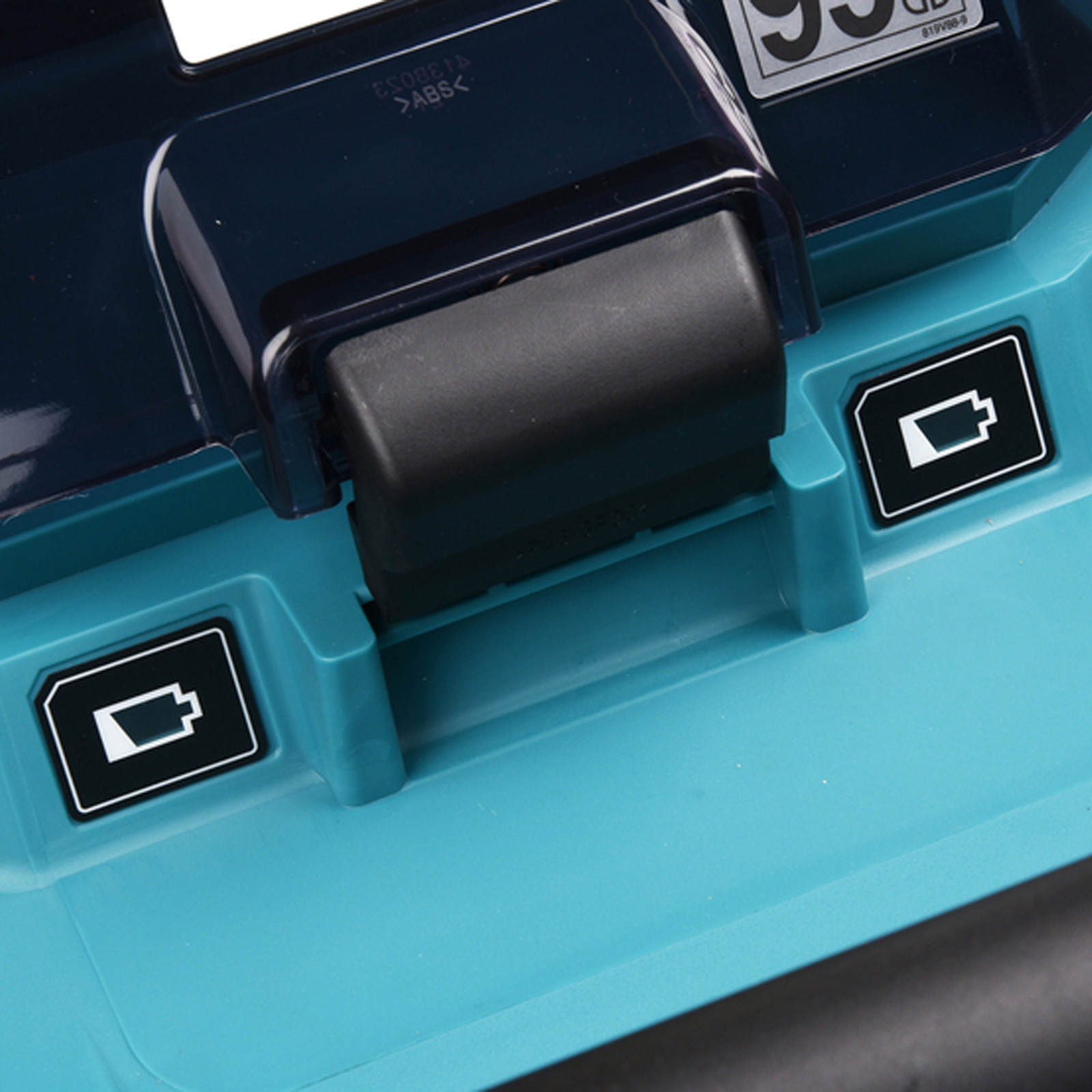 Eine Nahaufnahme zeigt ein Werkzeug-Akkuladegerät mit einem schwarzen Griff und Batteriesymbolen auf einer türkisfarbenen Oberfläche.
