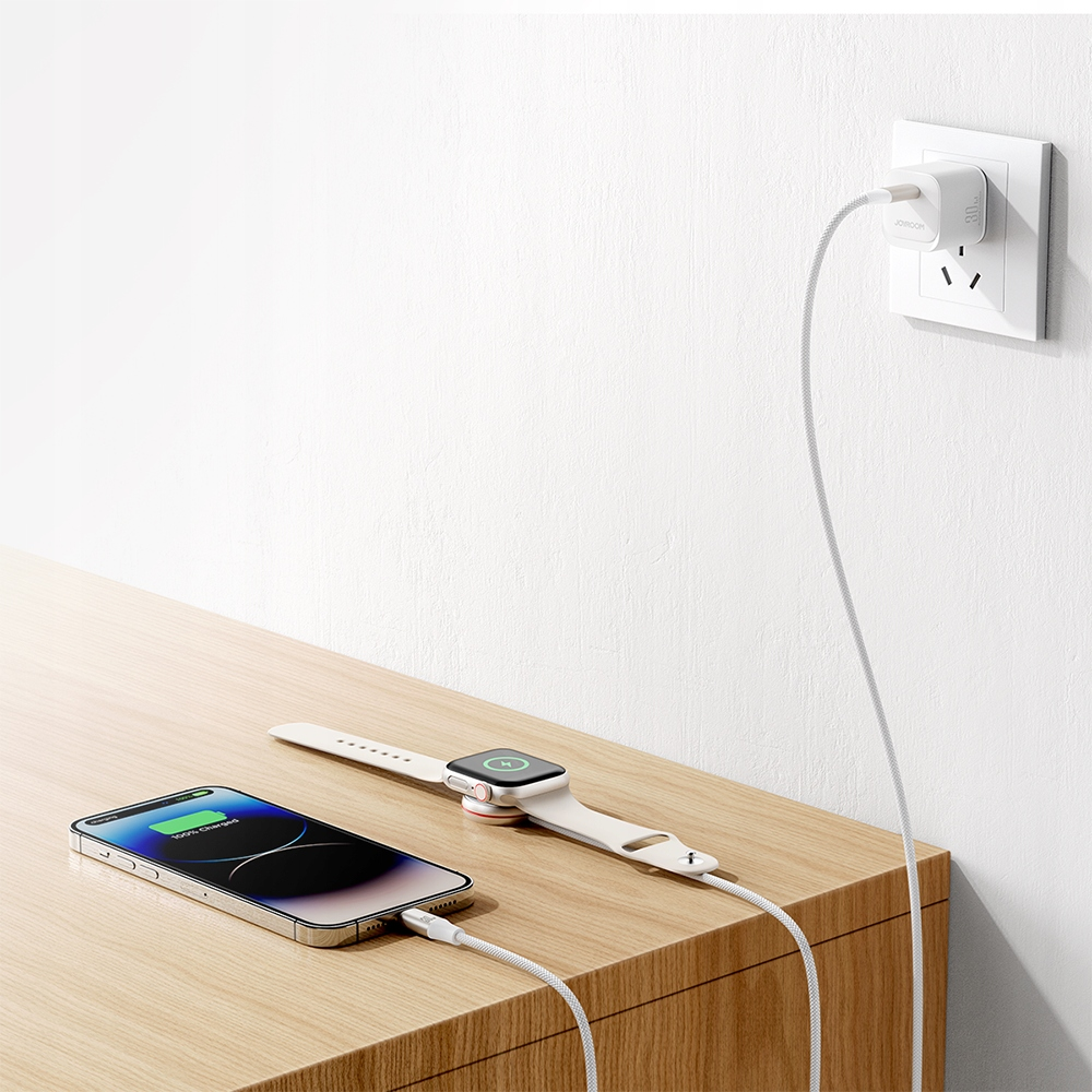 Bild eines Telefons und einer Uhr, die auf einem Holztisch mit einem weißen Ladekabel aufgeladen werden, das an einen Wandadapter angeschlossen ist.
