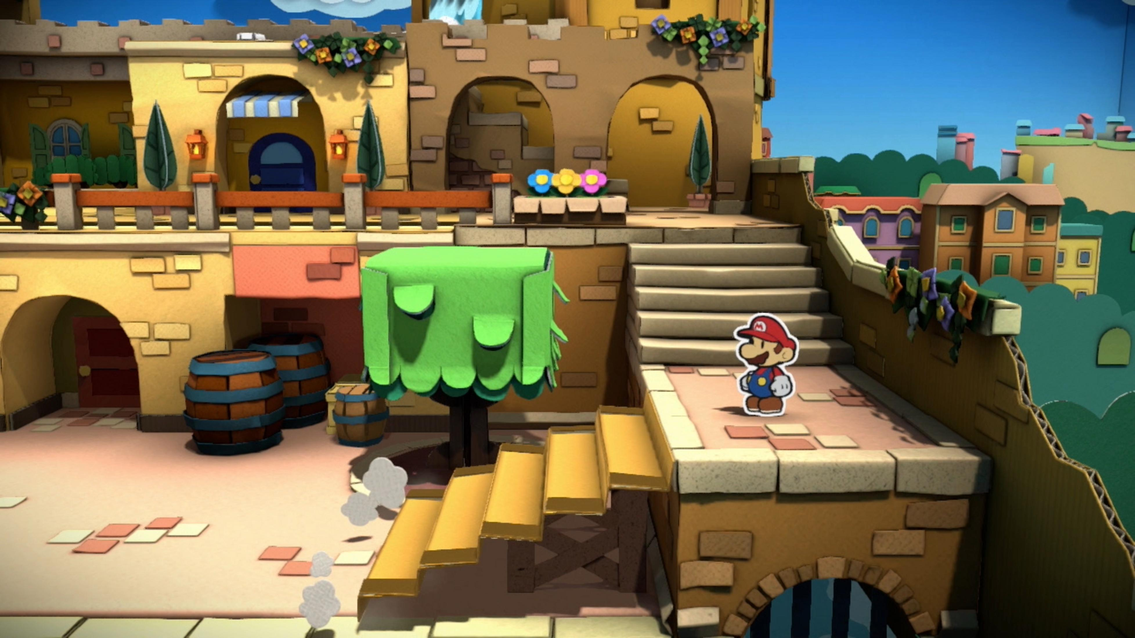 Scena z gry z Mario stojącym w pobliżu kartonowego budynku ze schodami i kolorowymi kwiatami.