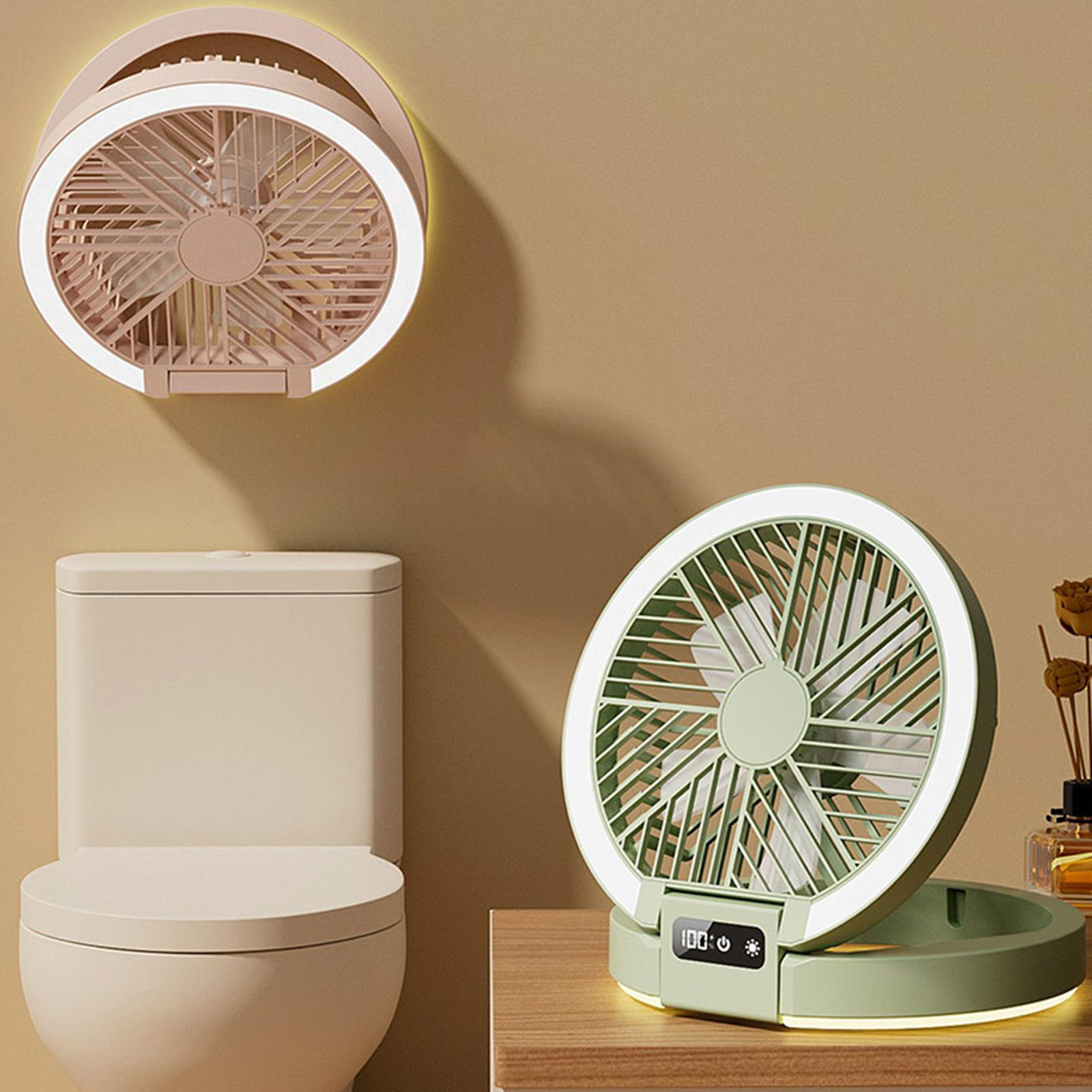 Zwei grüne Ventilatoren mit Ringlichtern, einer auf einem Tisch und einer an der Wand, neben einer Toilette.