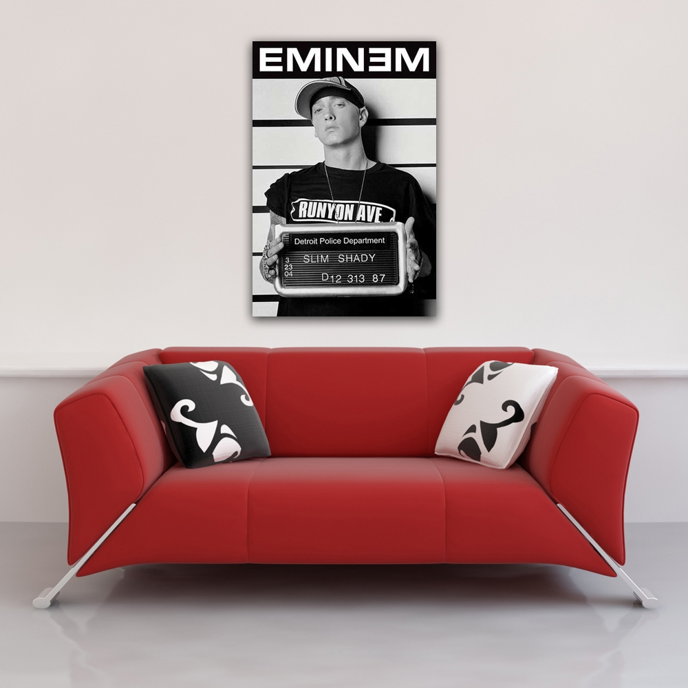 Ein rotes Sofa mit Kissen unter einem Poster von Eminem, der ein Polizeifoto hält.