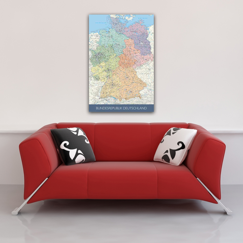 Ein rotes Sofa mit Kissen unter einem Poster einer bunten Karte von Deutschland.