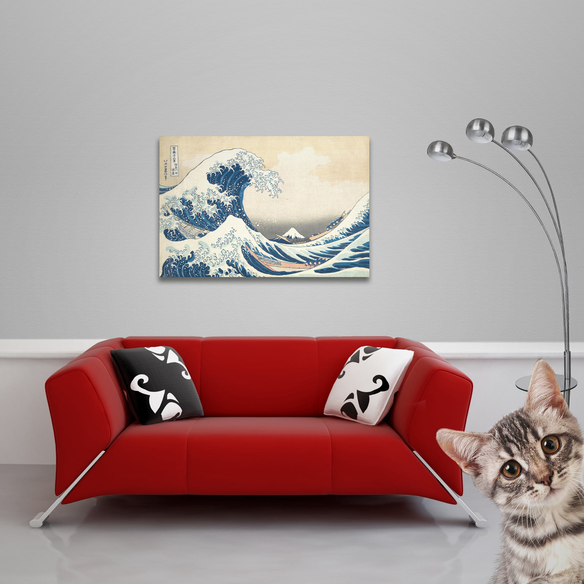 Rotes Sofa mit Zierkissen unter einem gerahmten Wellenbild. Eine Katze und eine moderne Lampe ergänzen die Szene.