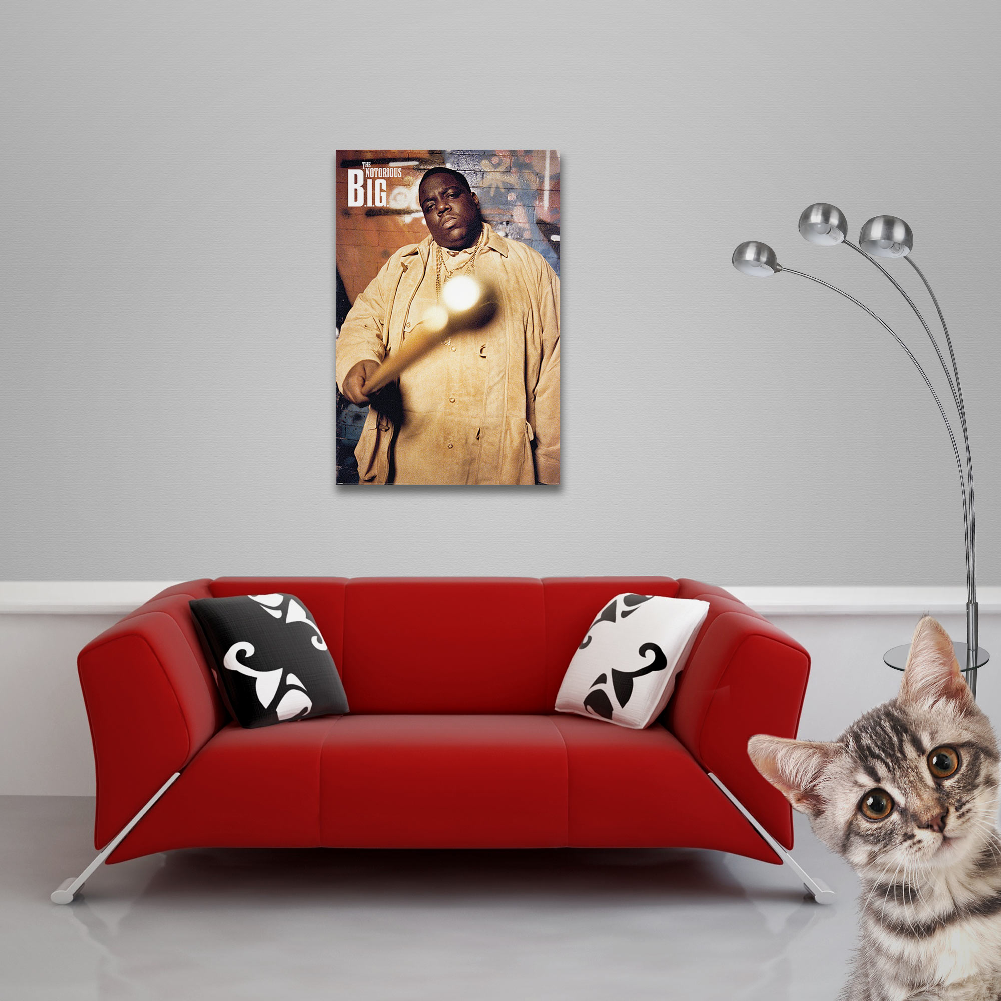 Ein rotes Sofa mit Zierkissen steht unter einem Poster von Notorious B.I.G., mit einer Katze und einer Lampe in der Nähe.