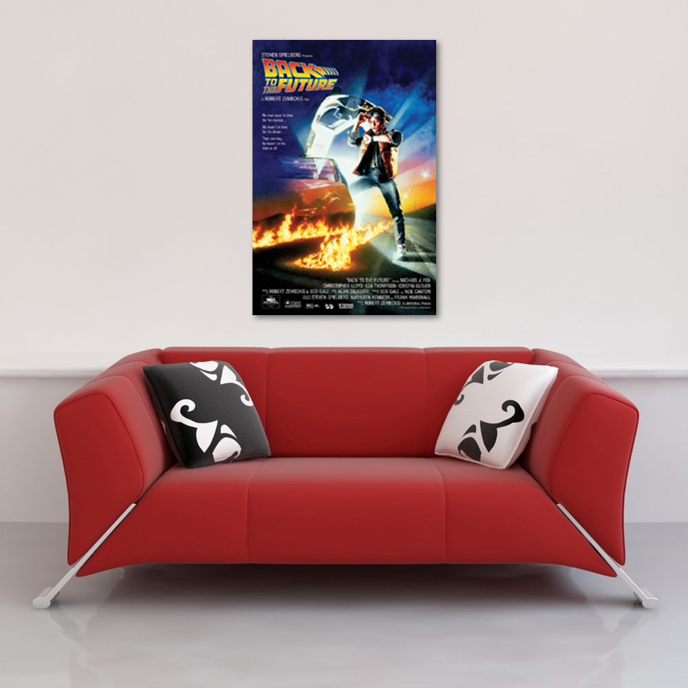 Ein rotes Sofa steht unter einem „Zurück in die Zukunft“-Filmplakat an einer weißen Wand, mit gemusterten Kissen auf dem Sofa.