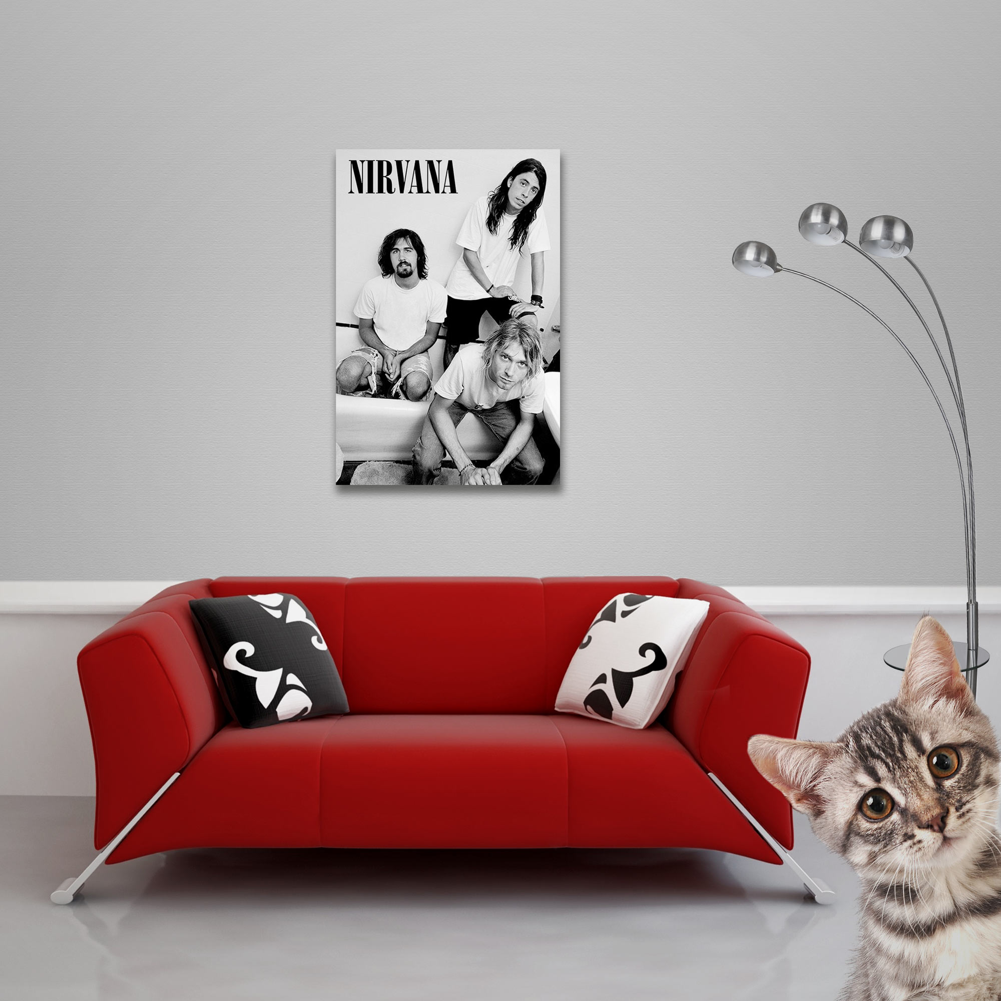Nirvana-Poster hängt über einem roten Sofa. Eine Katze lugt in den Rahmen. Eine Stehlampe ist rechts.
