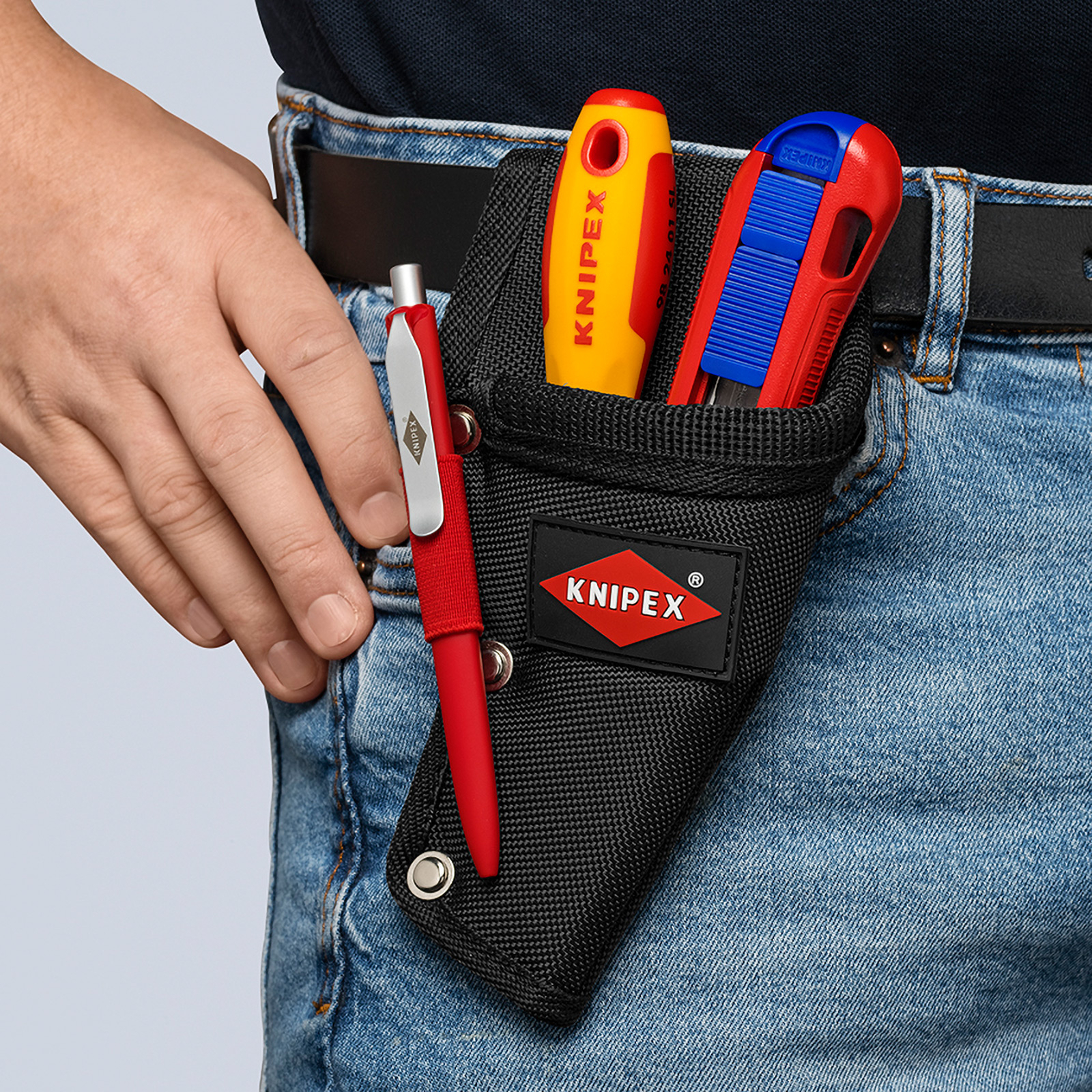 Ein Mann trägt ein schwarzes KNIPEX-Werkzeugholster an seinem Jeansgürtel, in dem sich Werkzeuge und ein roter Stift befinden.