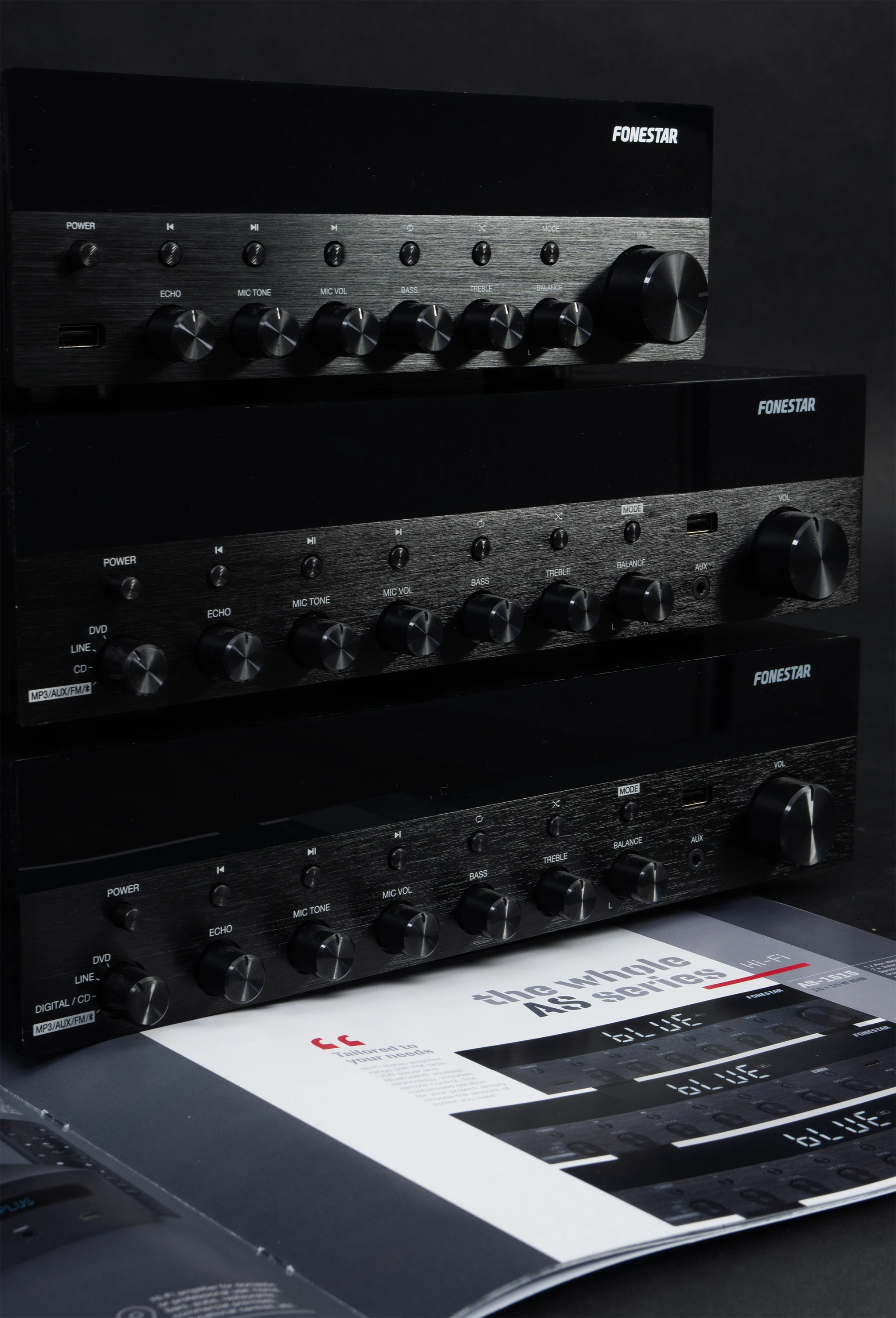 Tres amplificadores de audio Fonestar negros apilados con perillas de control y botones, sobre un folleto impreso.