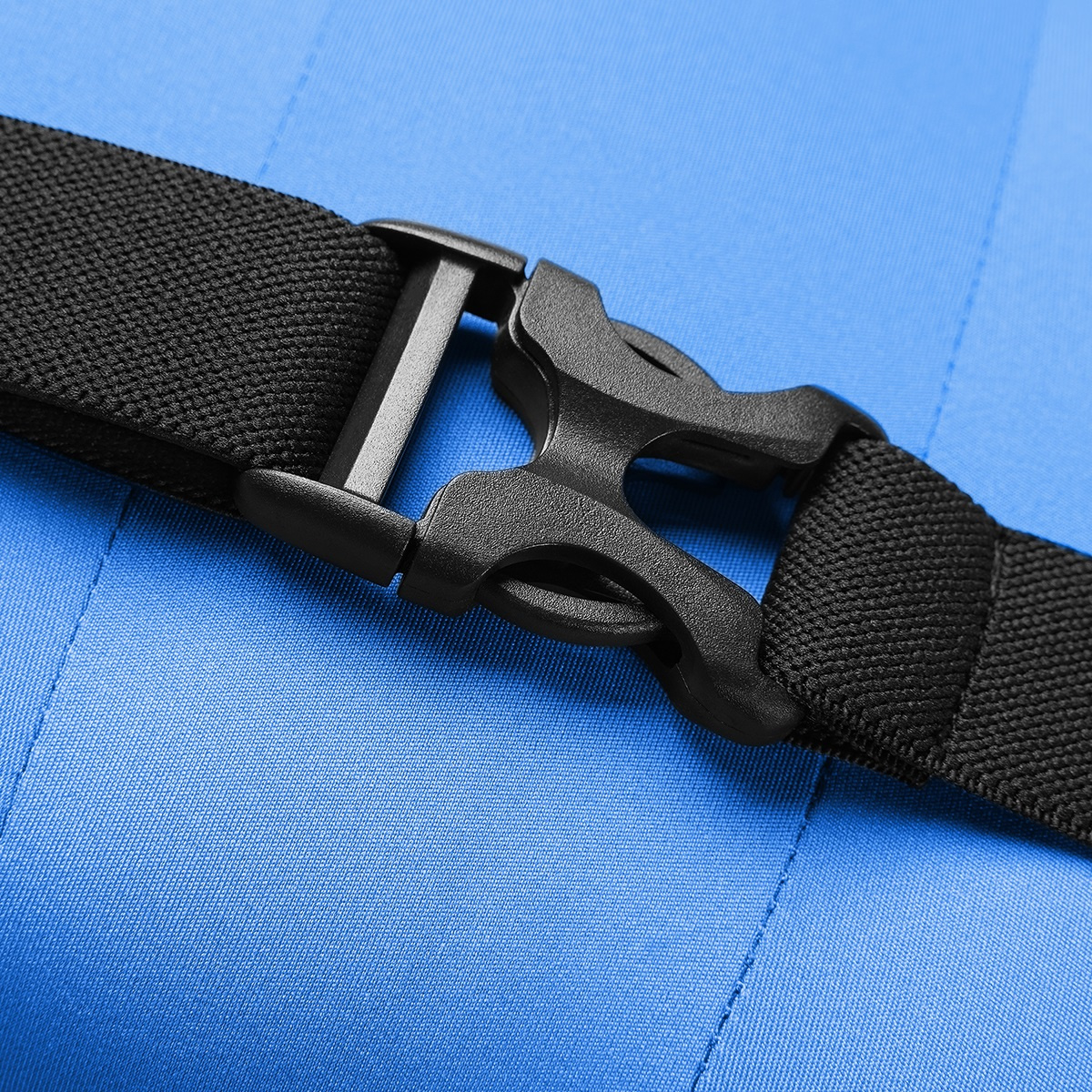 Zbliżenie pokazuje czarny plastikowy klips i pasek na tle niebieskiego materiału.