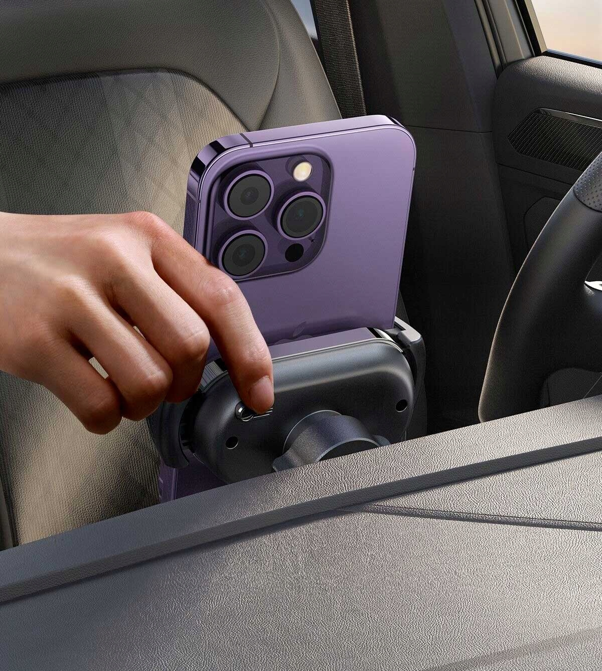 Ręka trzymająca fioletowy telefon w samochodzie, zamontowany na uchwycie samochodowym.