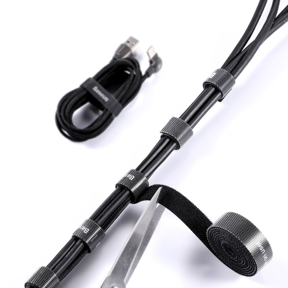 Czarne kable są uporządkowane za pomocą pasków na rzepy i nożyczek na białej powierzchni.