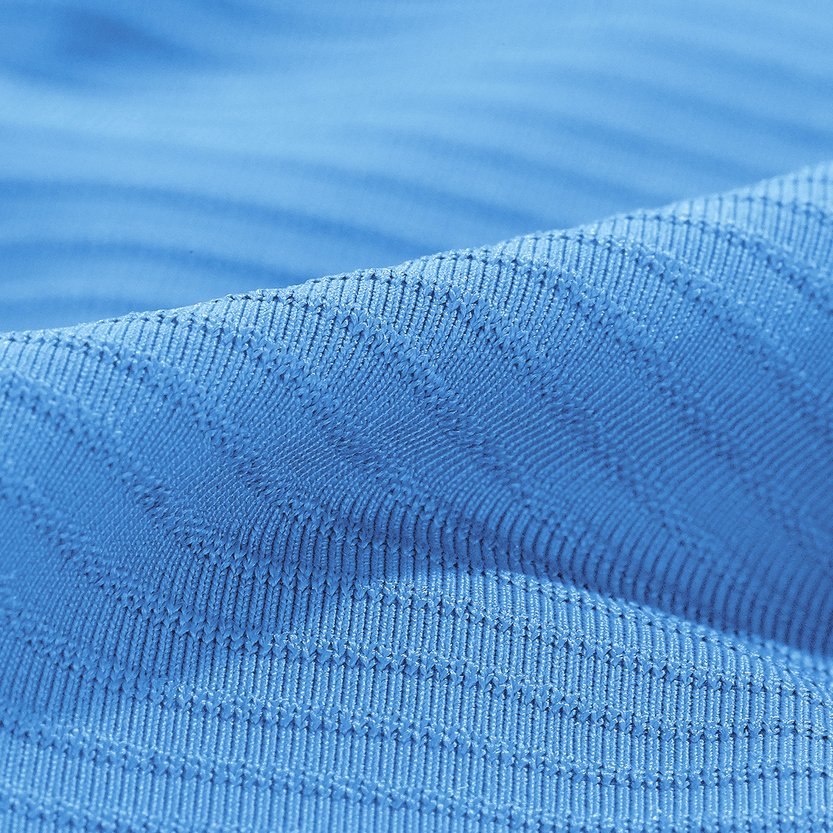 Zbliżenie jasnoniebieskiej tkaniny z subtelnym wzorem w paski. Miękki, teksturowany wygląd.