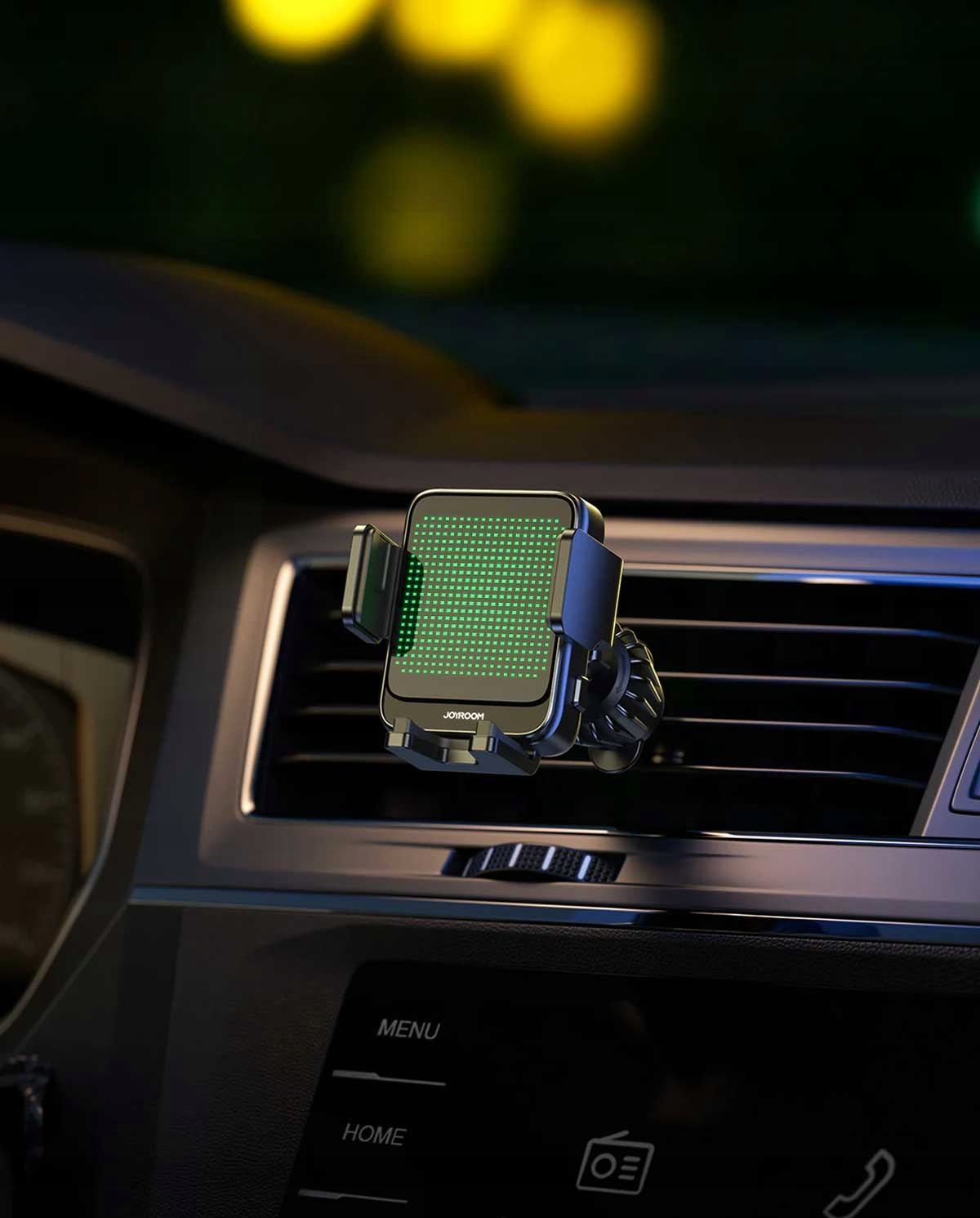 Uchwyt samochodowy do telefonu z zieloną siatką świetlną, zamontowany na kratce wentylacyjnej we wnętrzu samochodu w nocy.