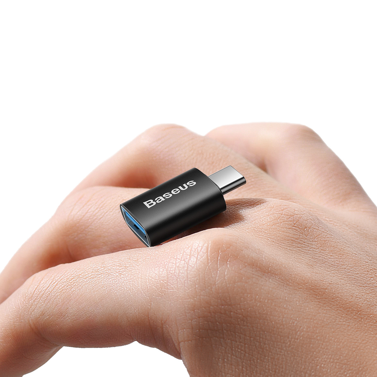 Gros plan d'un adaptateur USB Baseus noir sur une main, soulignant son design compact et sa facilité d'utilisation.