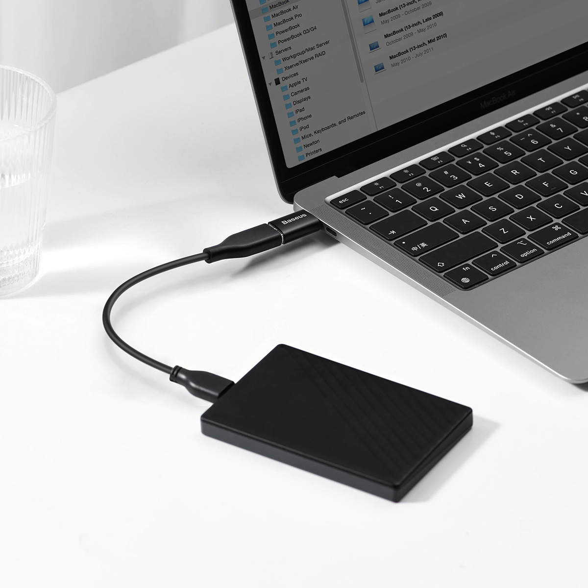 L'image montre un adaptateur Baseus connectant un disque dur externe à un MacBook, présentant la configuration du transfert de données.