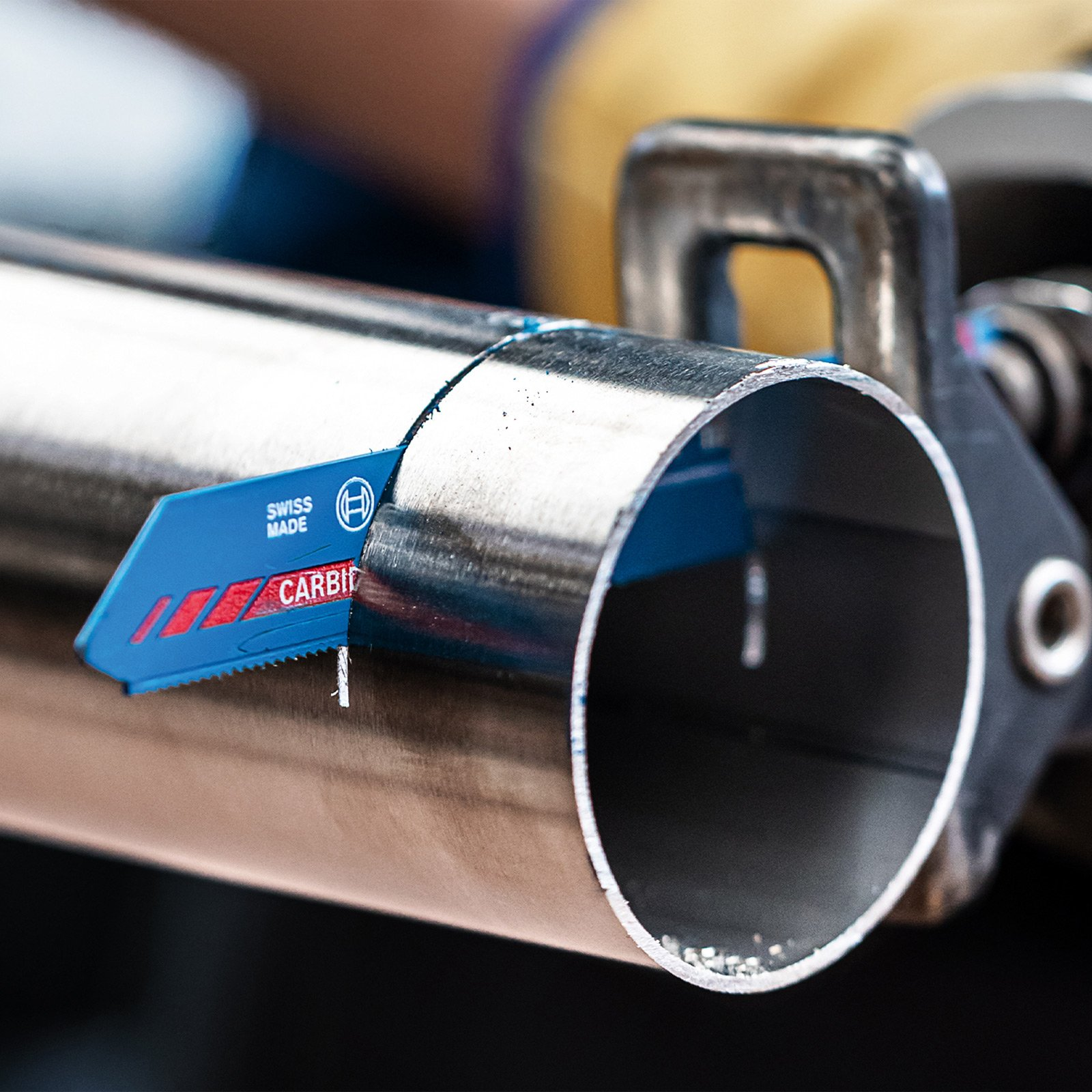 Ostrze Bosch EXPERT przecina metalową rurę trzymaną w zacisku, ukazując jej precyzję i trwałość.