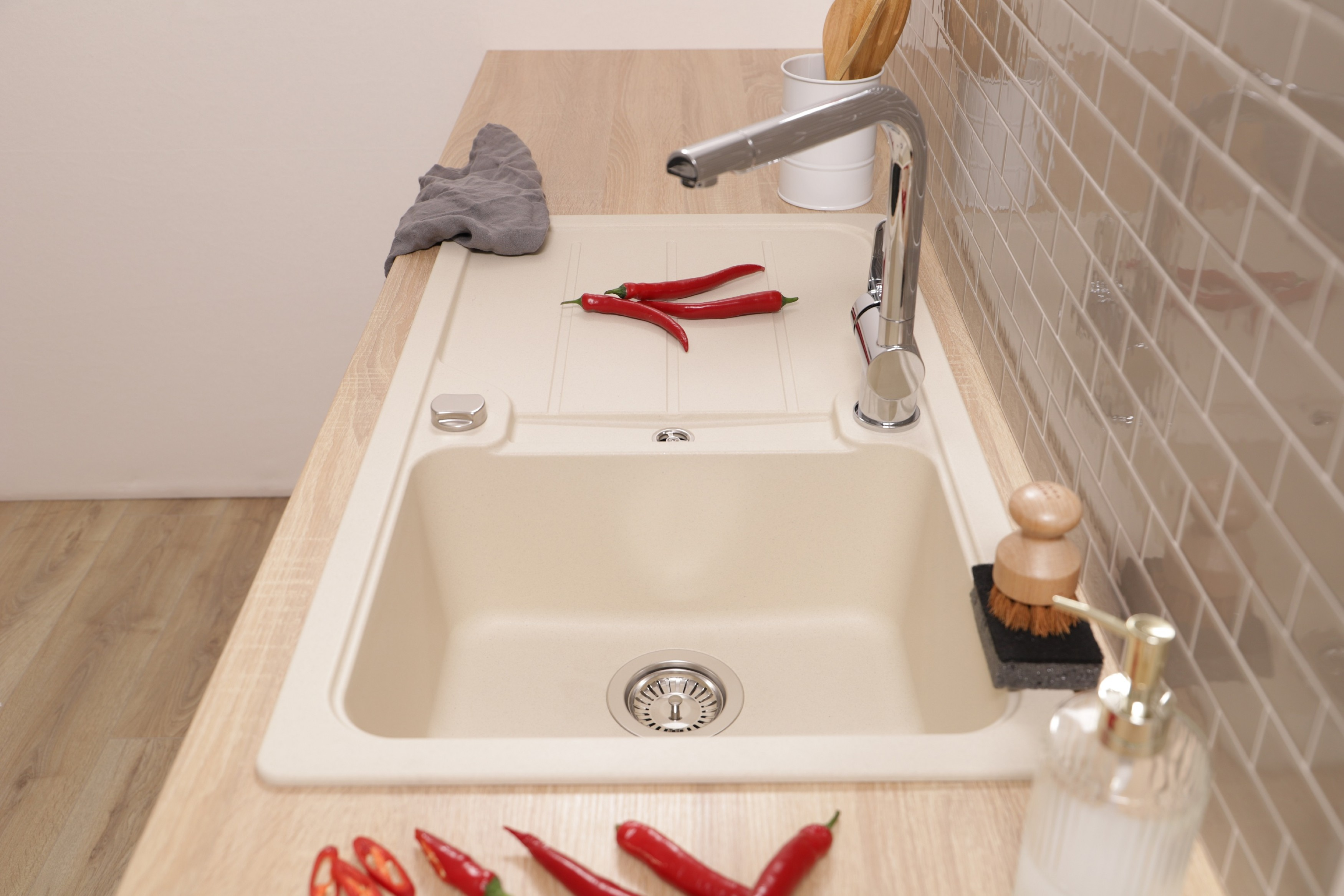 Küchenspüle mit Wasserhahn, rote Paprika, Holzoberfläche, und beigefarbene Fliesen.