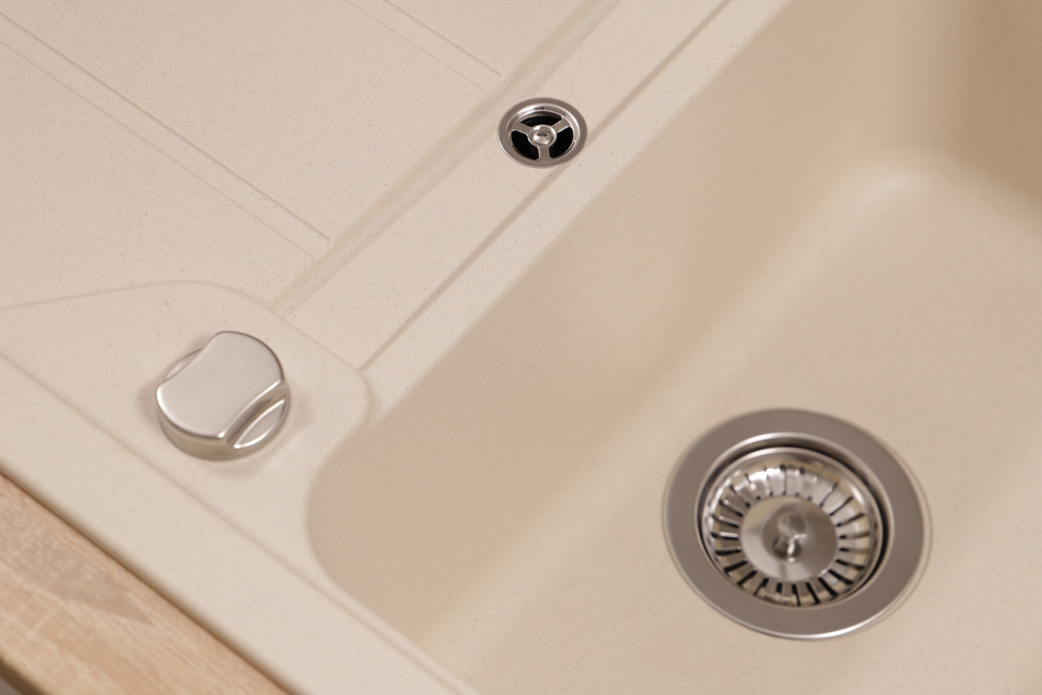Nahaufnahme eines Küchenbeckens mit Abfluss und kleinem Metallknopf.