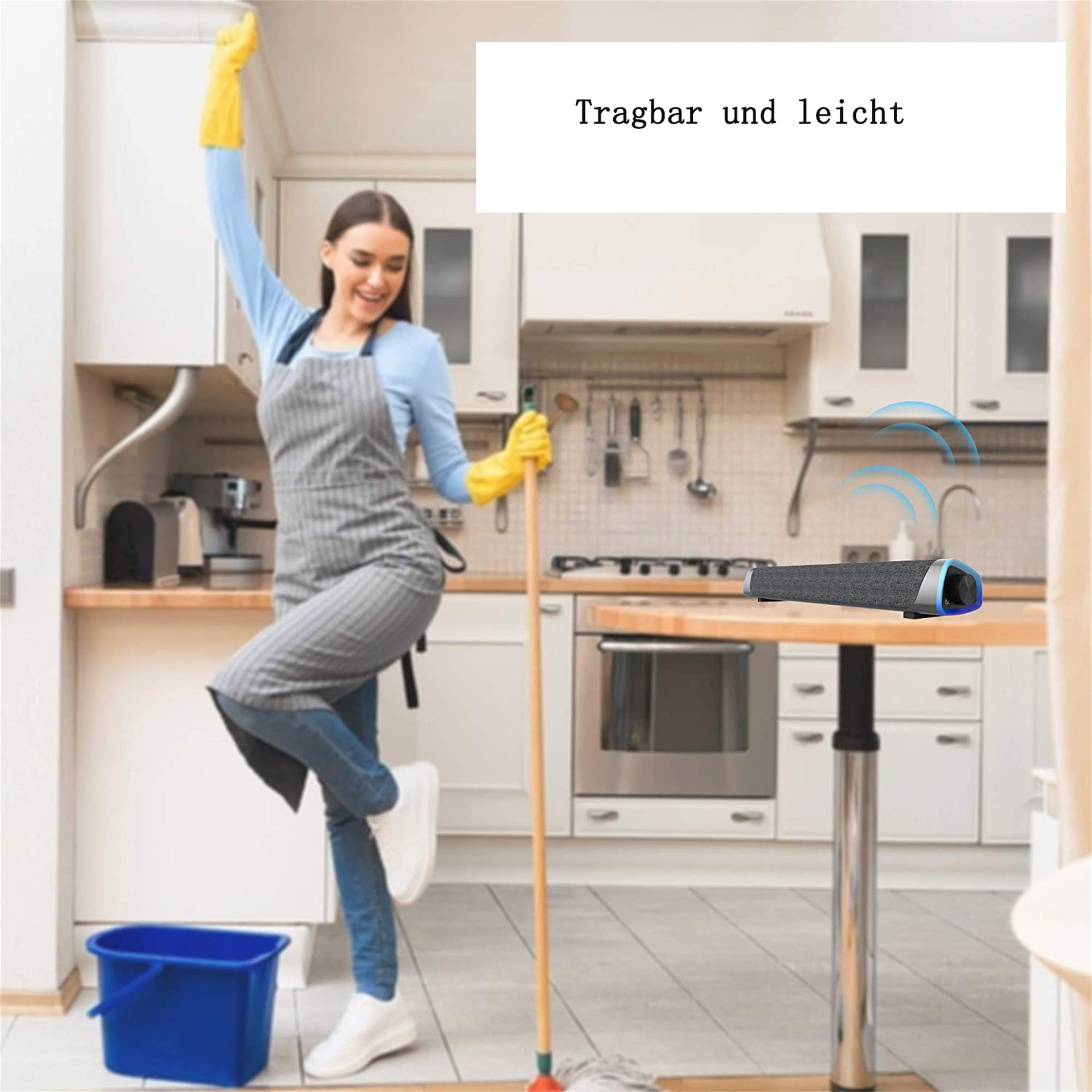 Frau putzt eine Küche mit einer grauen Soundbar auf einem Tisch, wobei die Portabilität und das leichte Design hervorgehoben werden.
