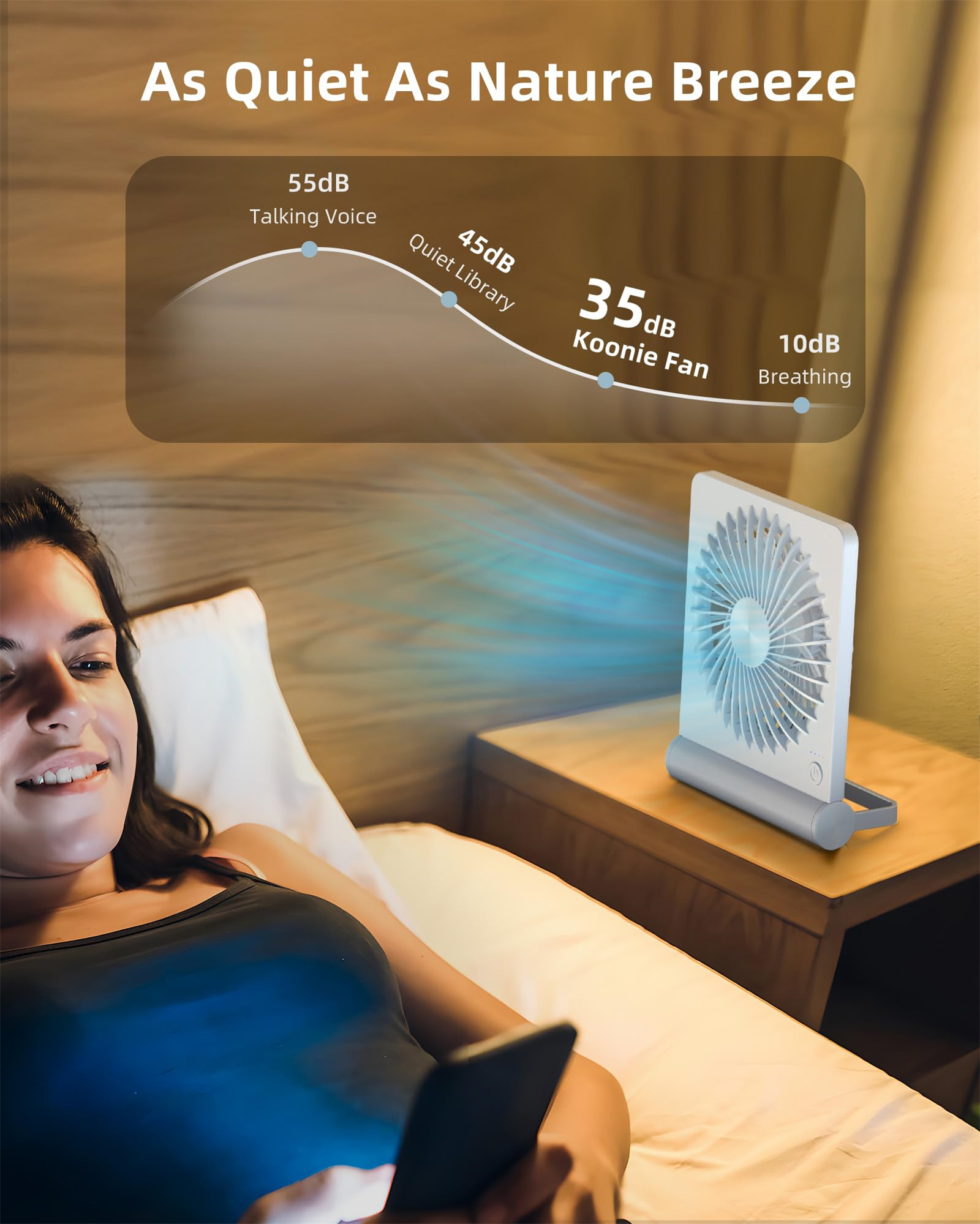 Eine Frau auf einem Bett schaut auf ein Telefon. Ein kleiner Ventilator steht auf einem Tisch neben ihr.