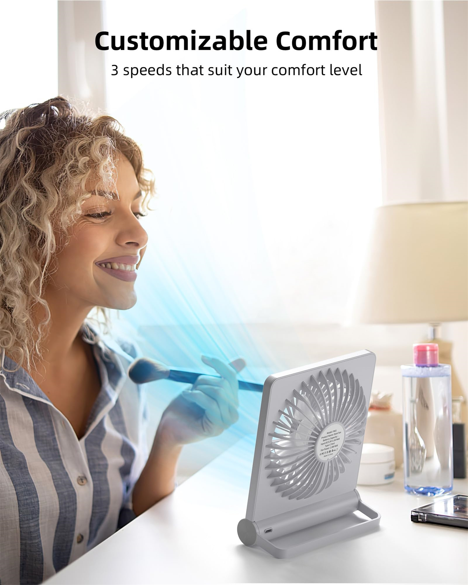 Eine Frau trägt Make-up vor einem Ventilator auf, wobei blaues Licht auf ihr Gesicht scheint.