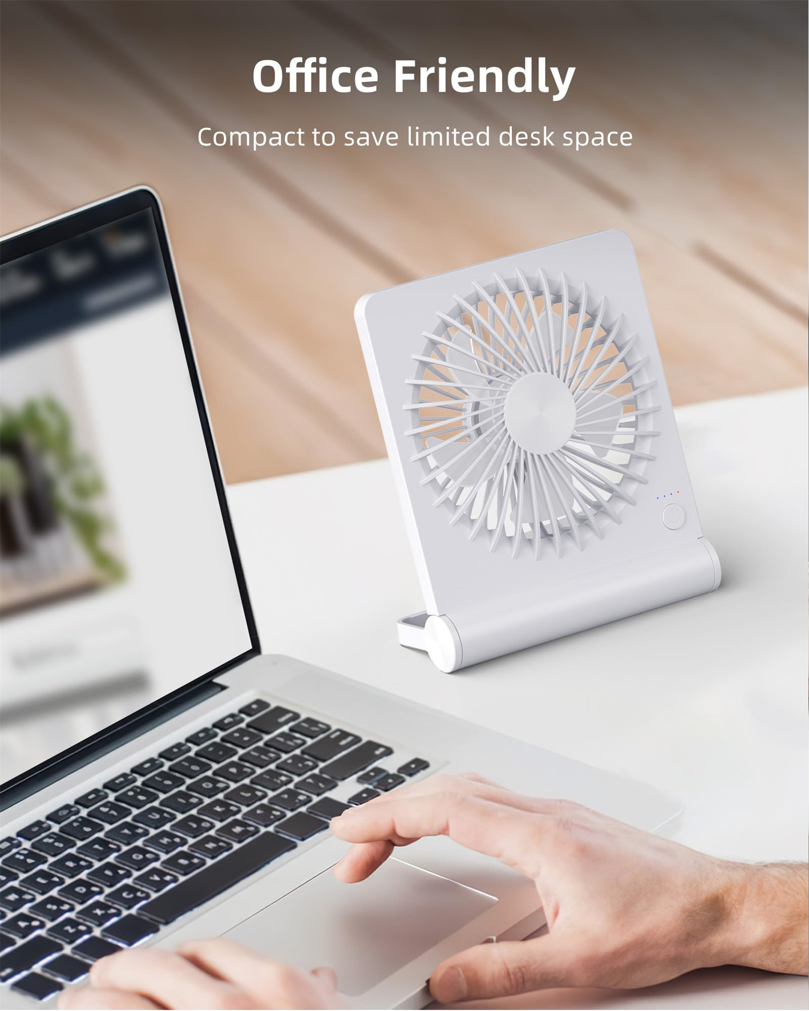 Ein kleiner weißer Ventilator steht auf einem Schreibtisch neben einem Laptop und einer Hand auf dem Trackpad.