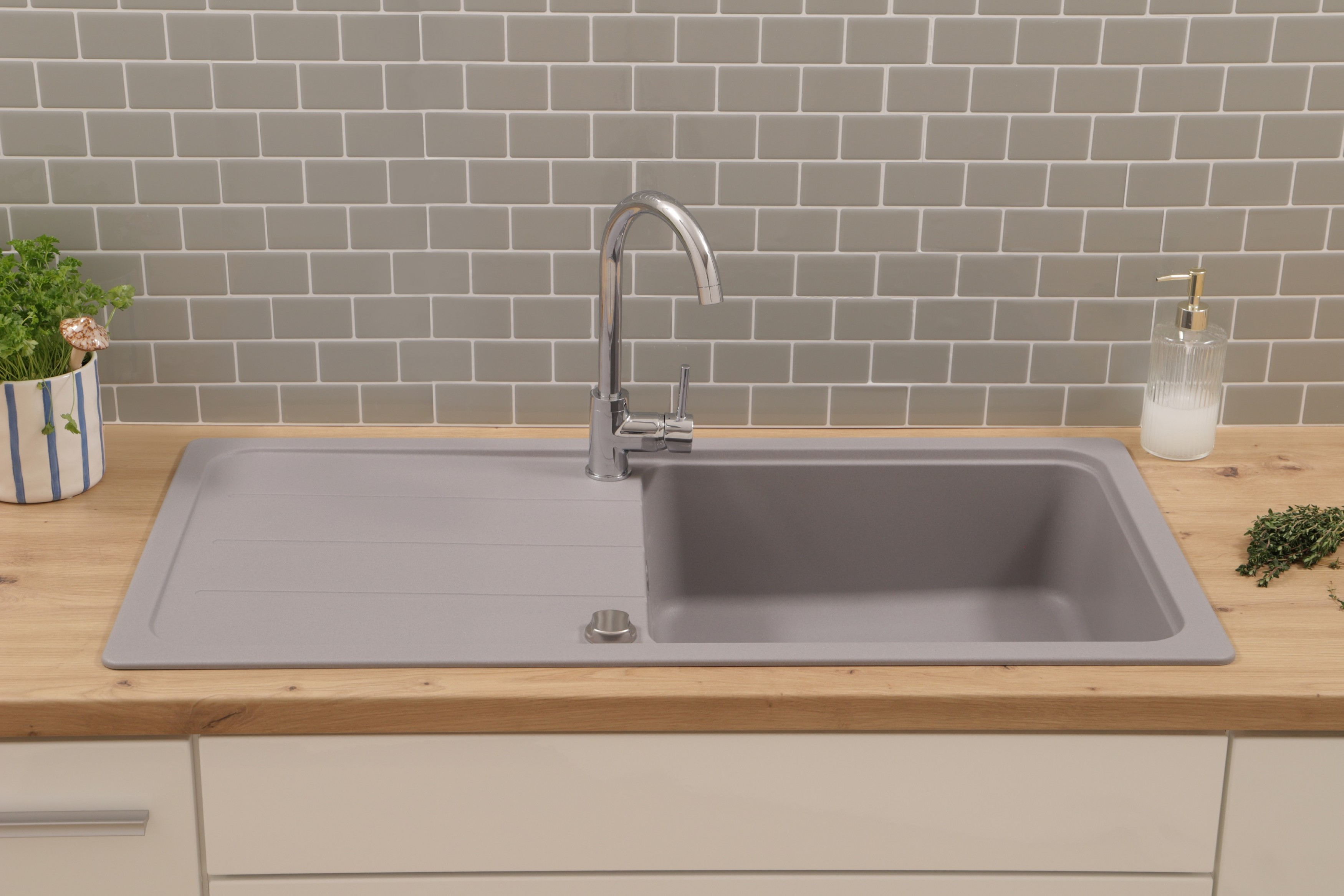 Ein graues Küchenbecken mit Wasserhahn. Das Waschbecken befindet sich auf einer Holzplatte.