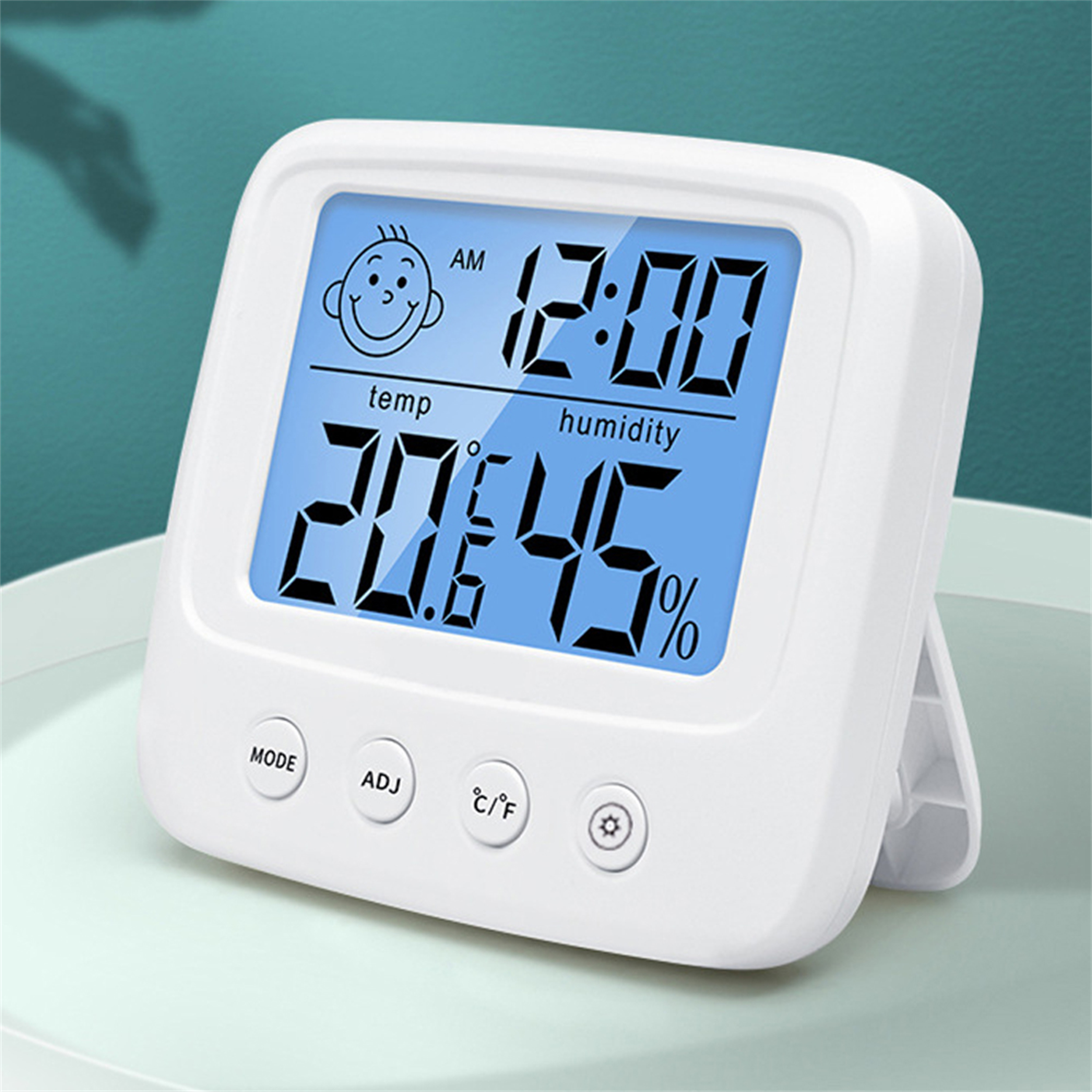 Digitales Thermometer, das Temperatur und Luftfeuchtigkeit auf einem hellblauen Bildschirm anzeigt, auf einem Tisch.