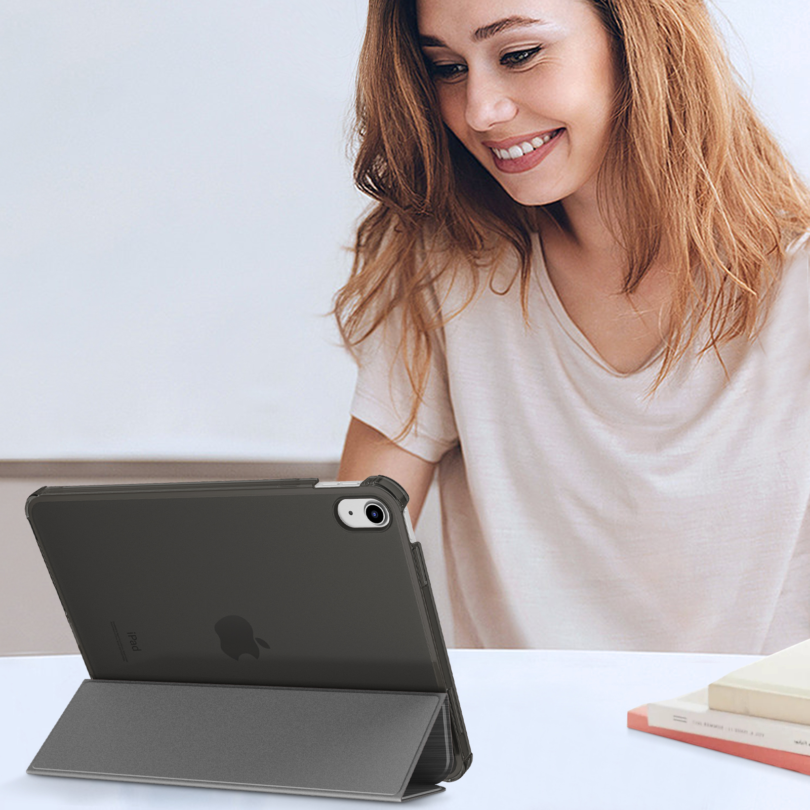 Frau benutzt ein iPad in einer Hülle. Sie lächelt und hält das iPad auf ihrem Schoß. Die Hülle ist zusammengeklappt.