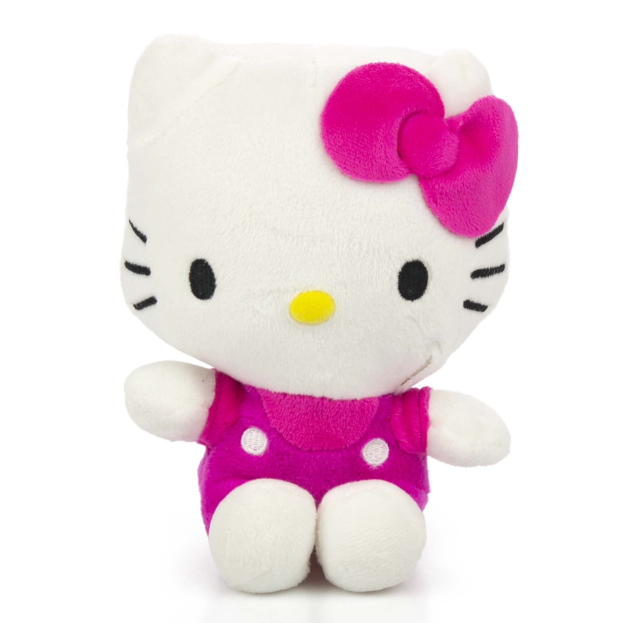 Eine weiße Plüsch-Hello Kitty-Puppe mit rosa Schleife und Outfit, stehend auf weißer Oberfläche.