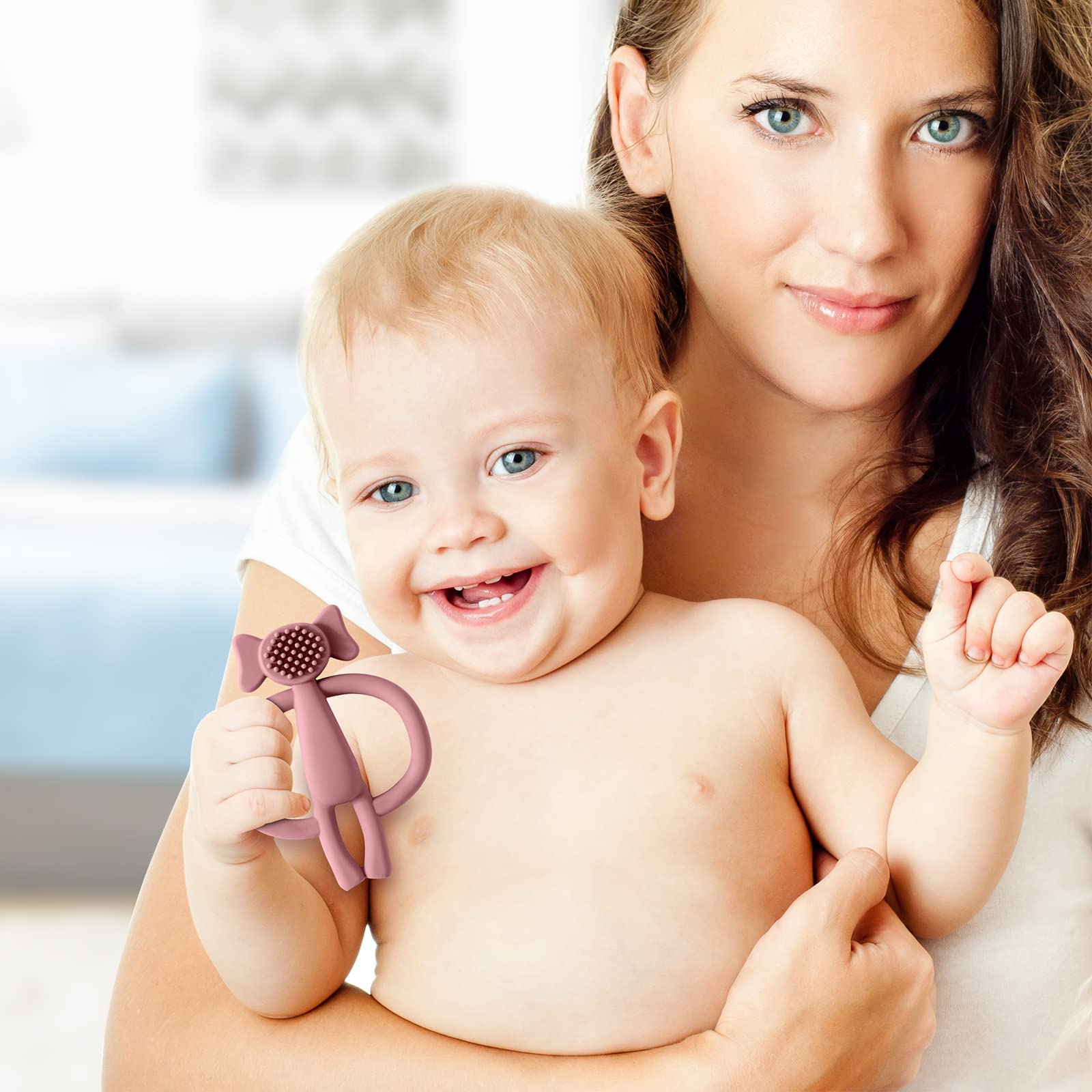 Eine Frau hält ein Baby. Das Baby lächelt und hält ein rosa Spielzeug.