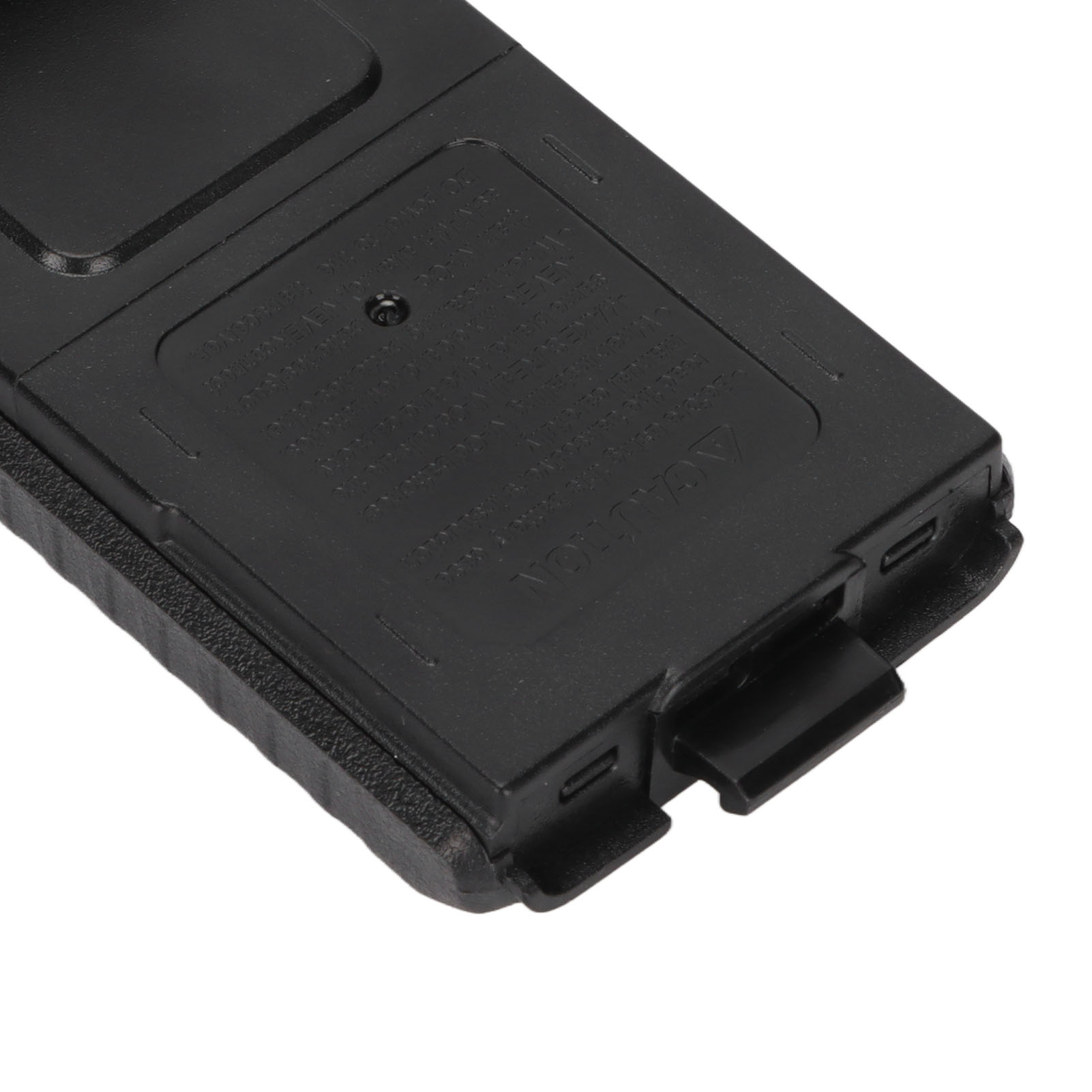 Nahaufnahme der Unterseite eines schwarzen Batteriegehäuses mit einer strukturierten Oberfläche und Verriegelungsmechanismen.