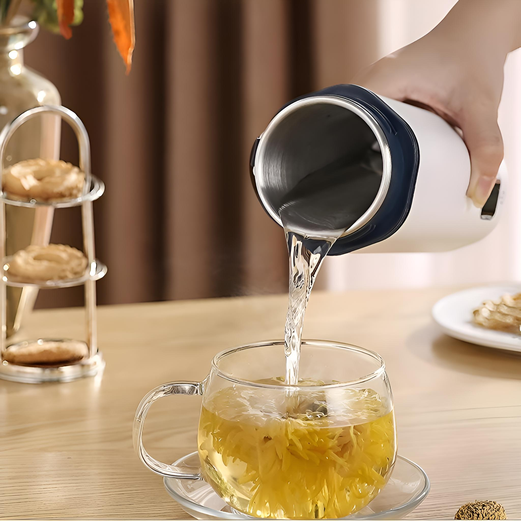 Eine Person gießt Wasser aus einem weißen Reisebecher in ein Glas Tee.