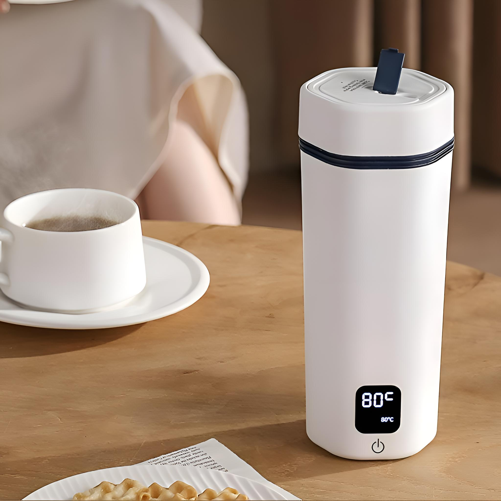 Ein weißer Reisebecher mit digitaler Anzeige von 80°C. Im Hintergrund eine weiße Tasse und Untertasse.