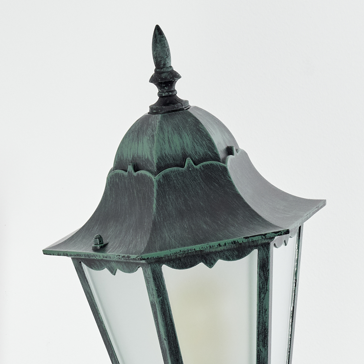 Nahaufnahme der Oberseite der Außenlampe. Grün, mit Glas und dekorativer Spitze.