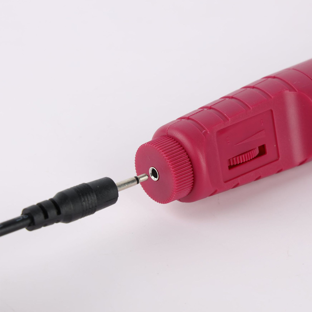 Eine Nahaufnahme eines rosa elektrischen Werkzeugs, in das ein schwarzes Kabel eingesteckt ist, vor einem weißen Hintergrund.