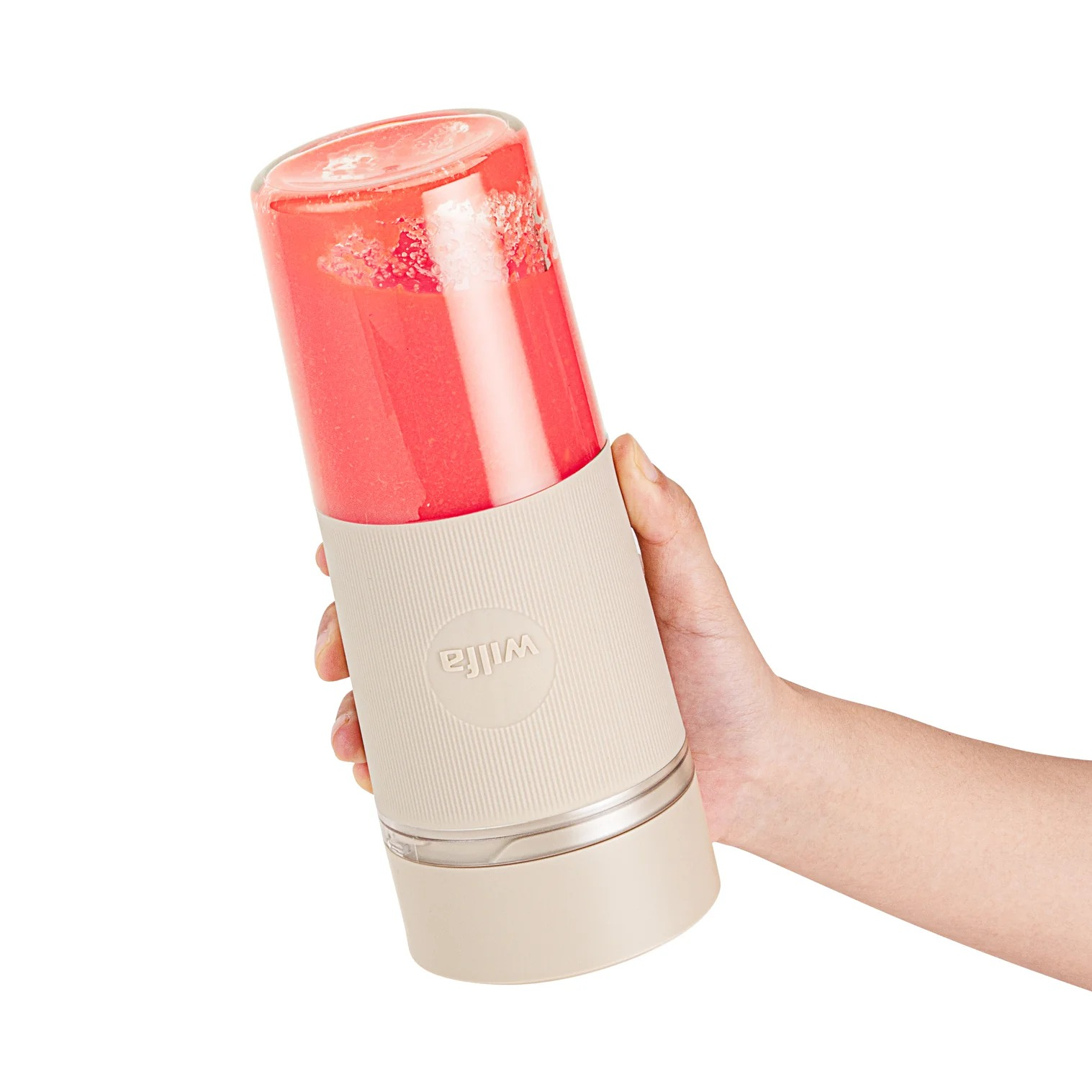 Hand hält einen Mixer mit roter Flüssigkeit. Der Mixer hat einen beigen Sockel.