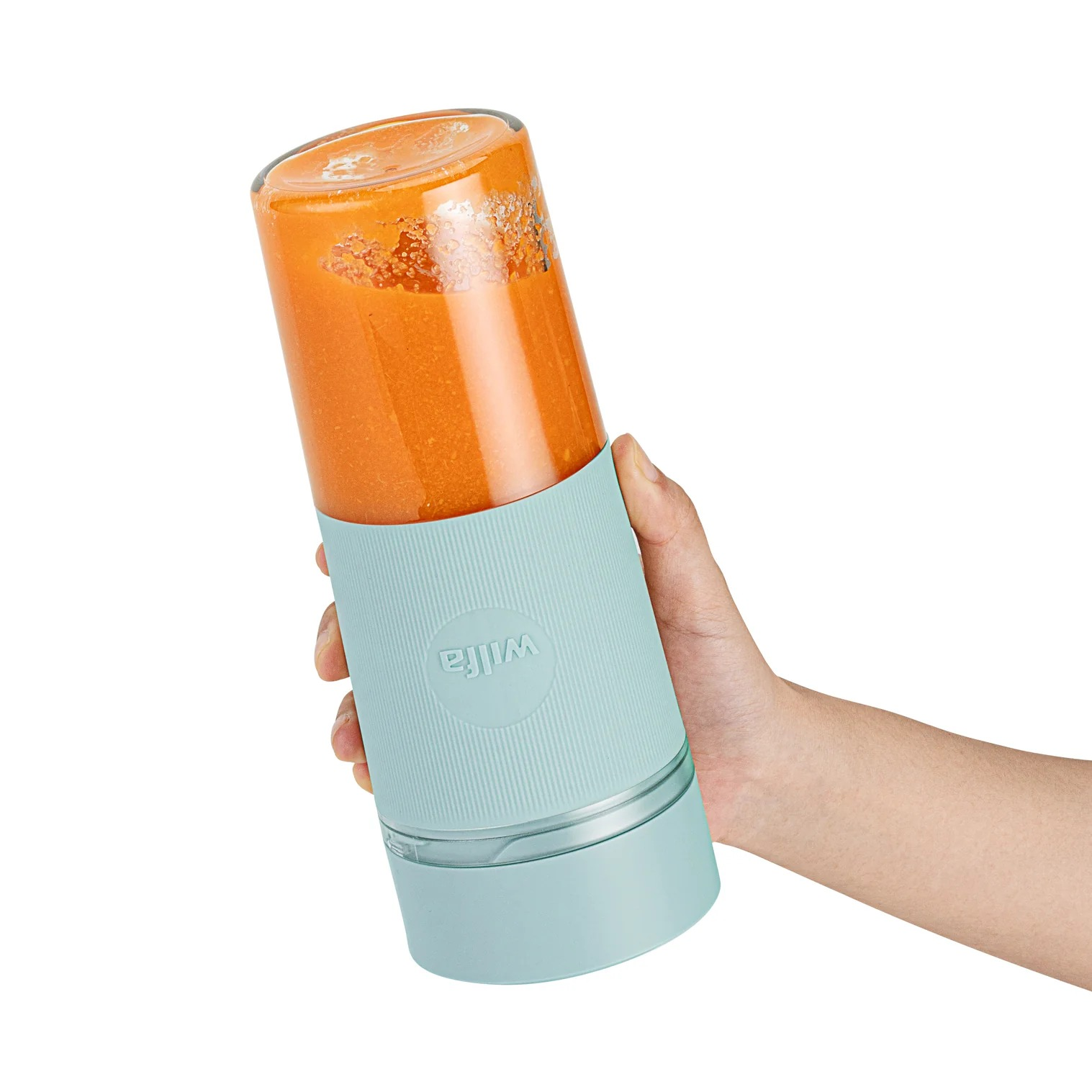 Hand, die eine türkisfarbene und transparente Wilfa-Mixerflasche hält, die mit orangefarbenem Smoothie gefüllt ist.
