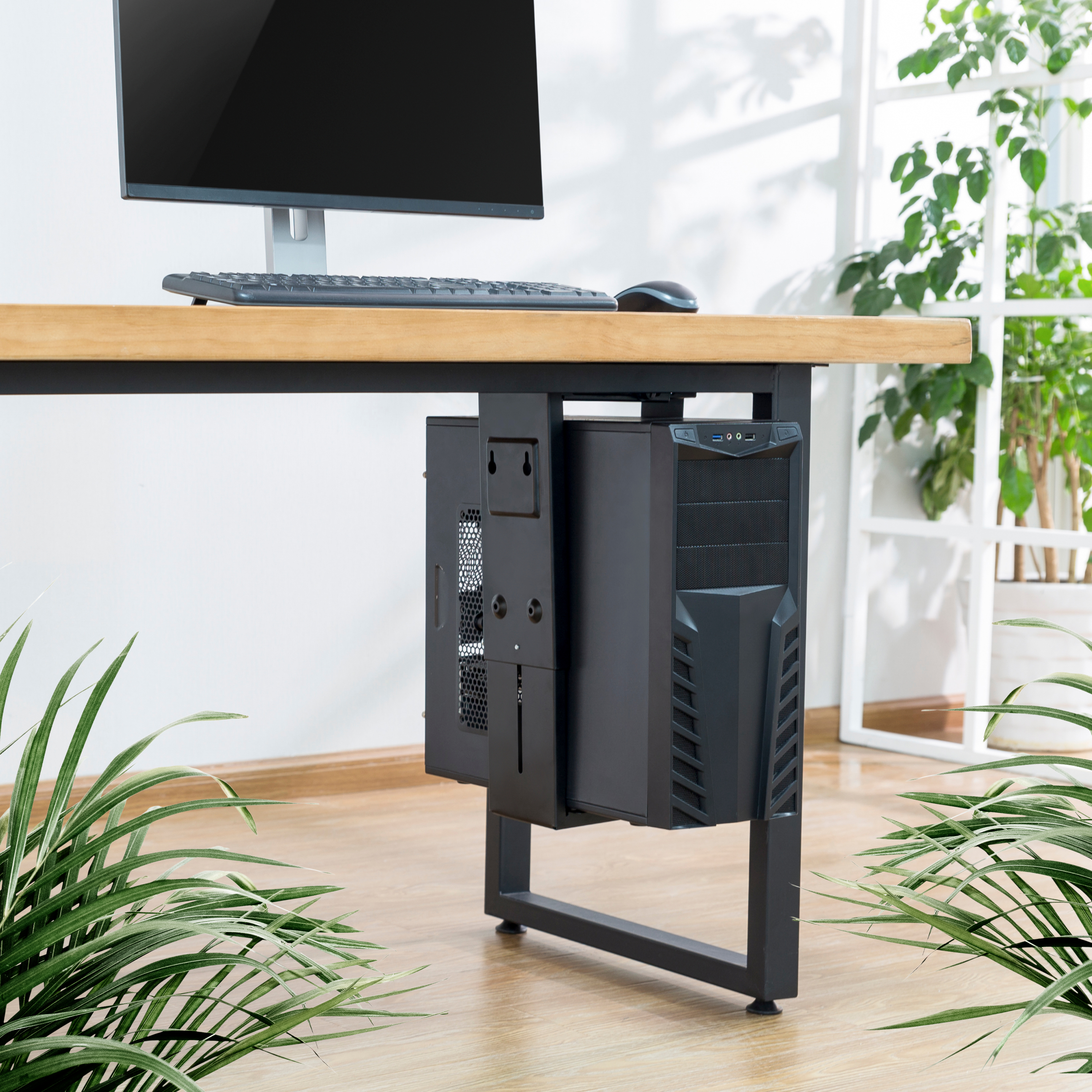 Ein an einem Schreibtisch befestigter CPU-Halter mit einem sichtbaren Computertower, Monitor und Pflanzen.