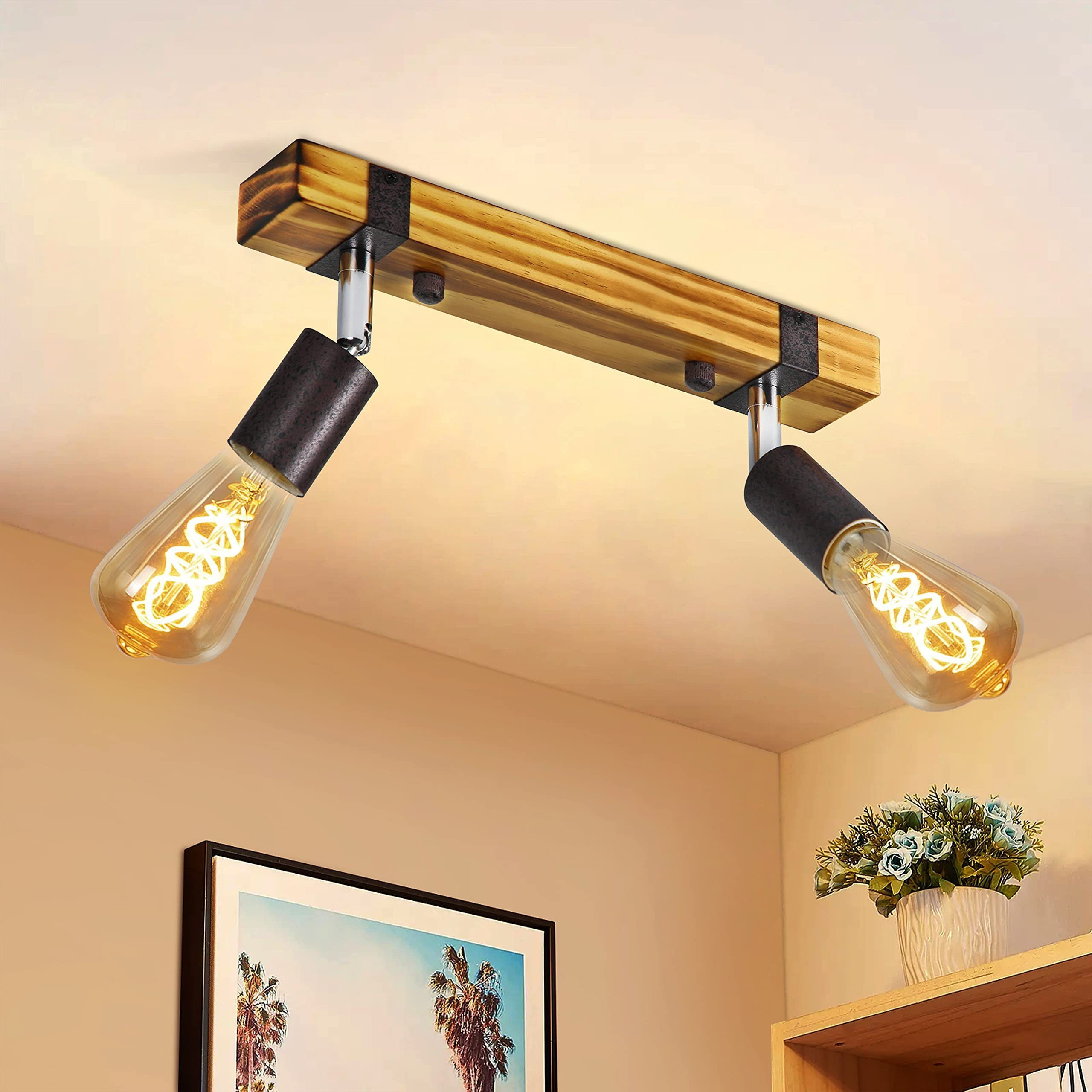 Ein Wohnzimmer mit zwei Lampen, die an einem Holzbalken hängen, einem grauen Sofa und einer Topfpflanze.