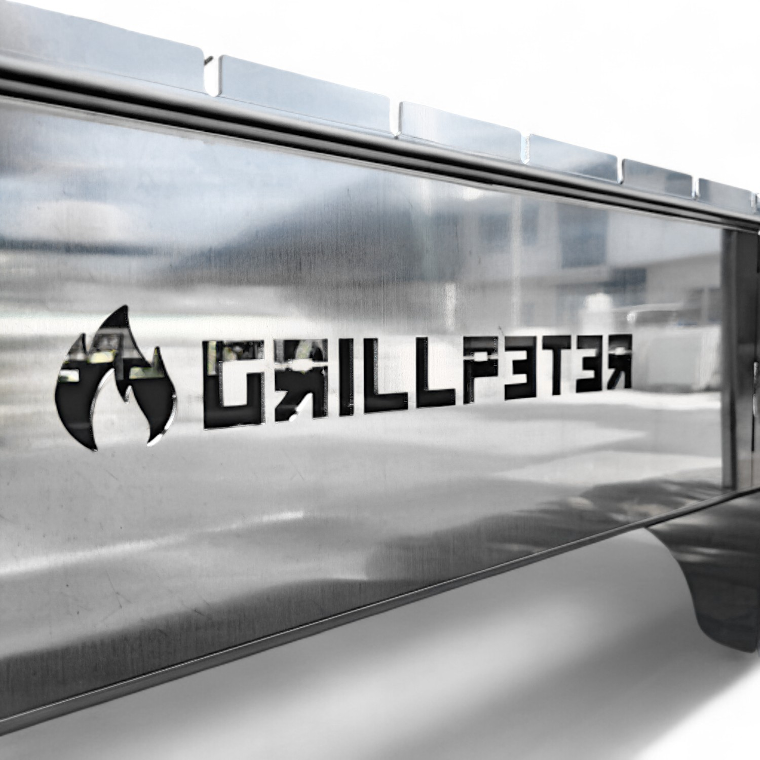 Nahaufnahme eines silbernen tragbaren Grills mit dem Text "GRILLFSTER" an der Seite.