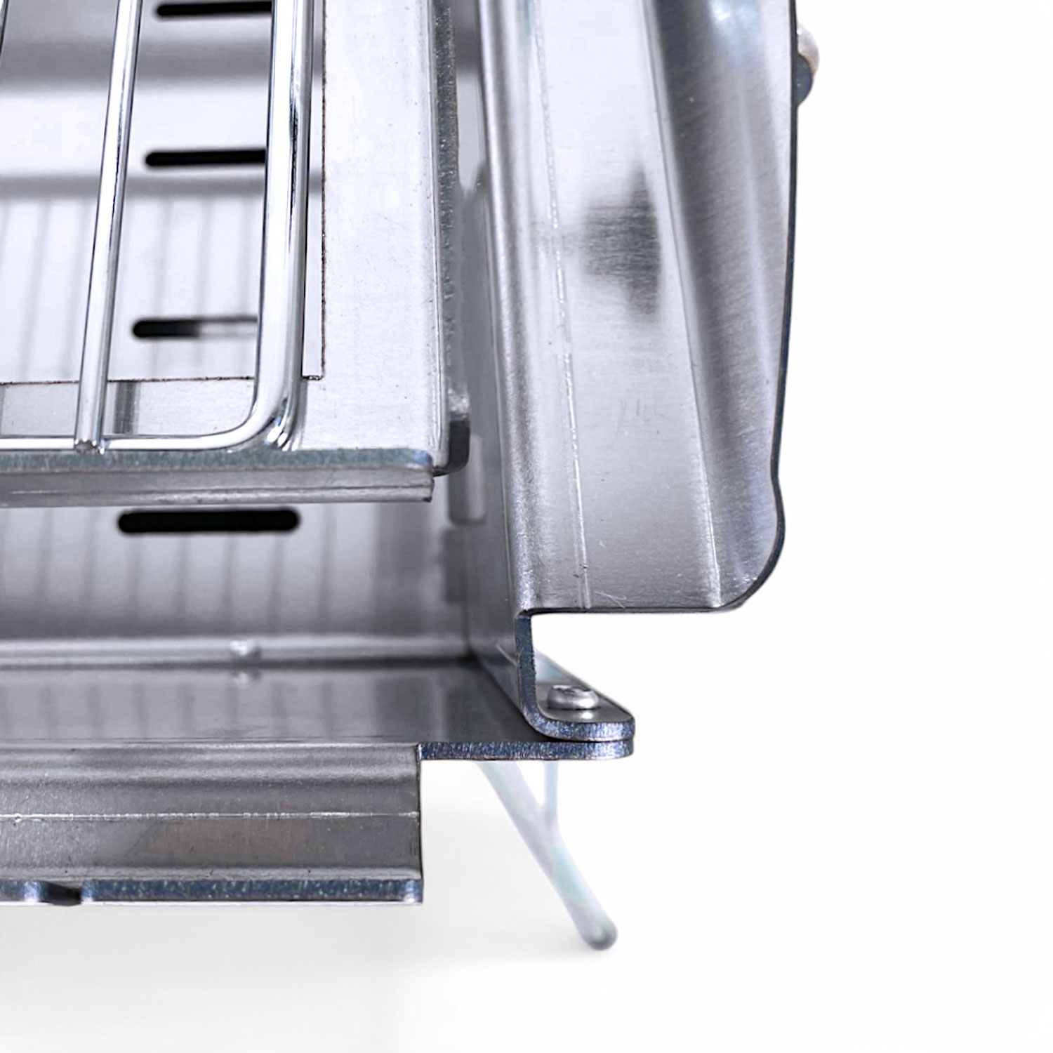 Eine Nahaufnahme der Ecke eines Metallgrills mit einem weißen Hintergrund.