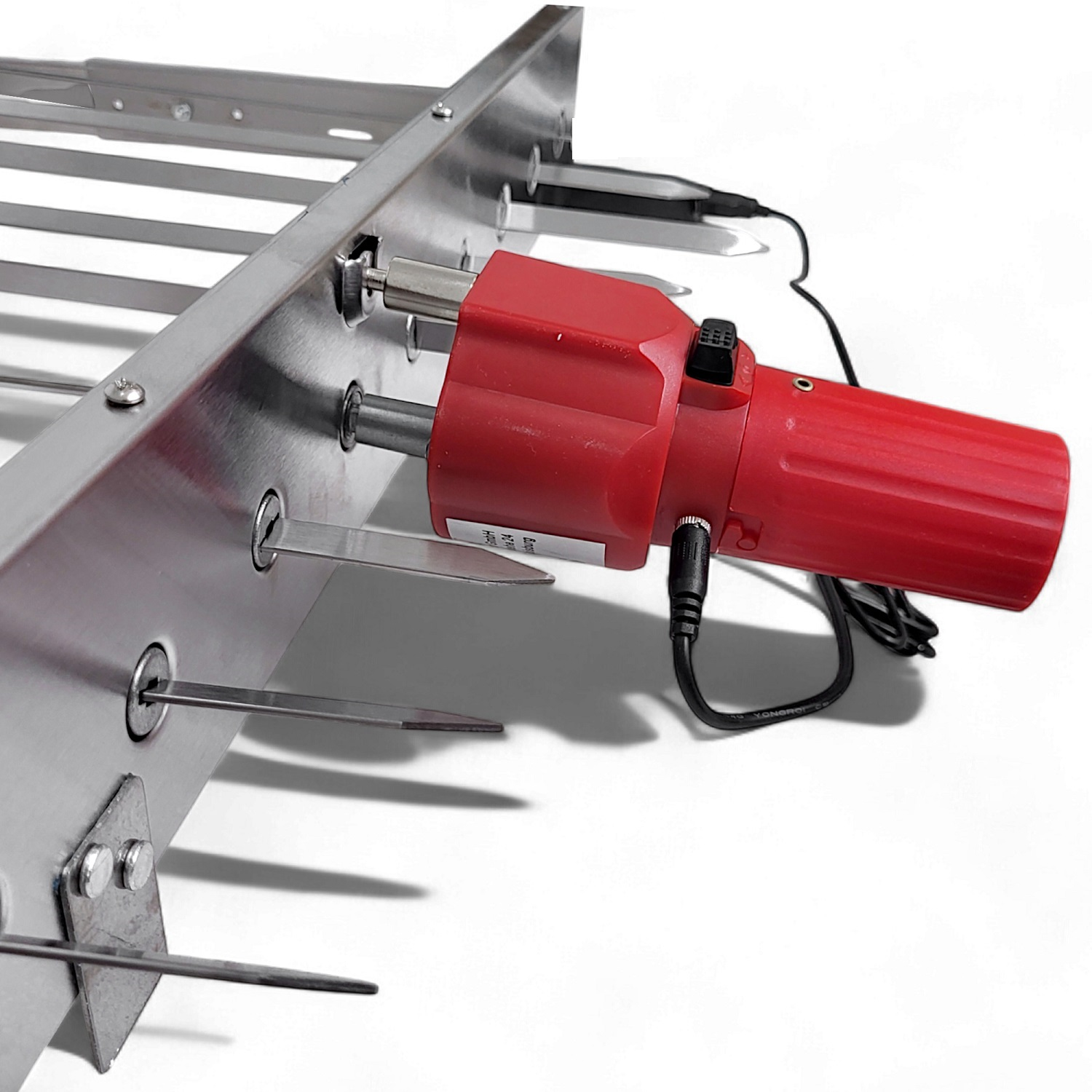 Eine Nahaufnahme eines roten Motors, der an einem Metallgrill mit Spießen befestigt ist.
