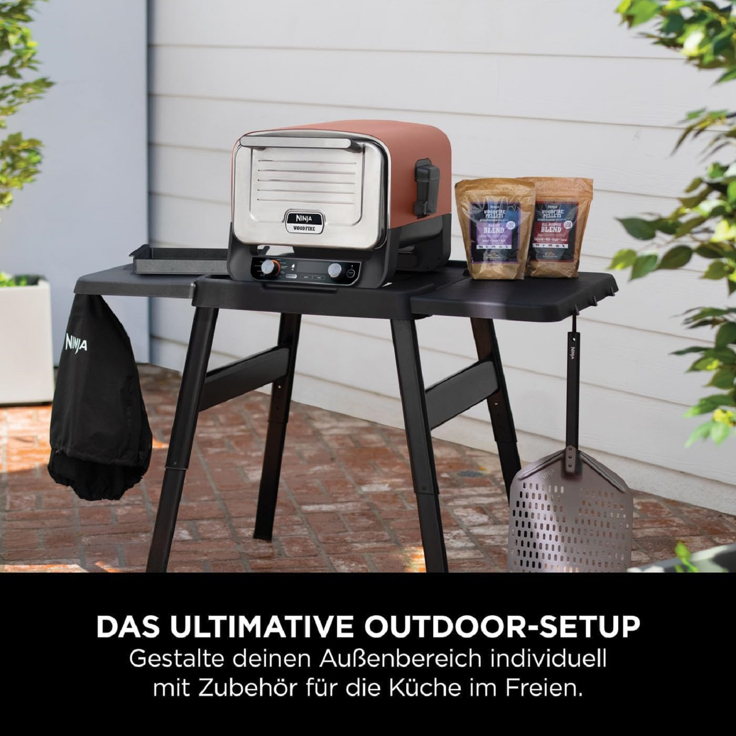 Una configuración de cocina al aire libre con un horno de pizza, mesa y accesorios.