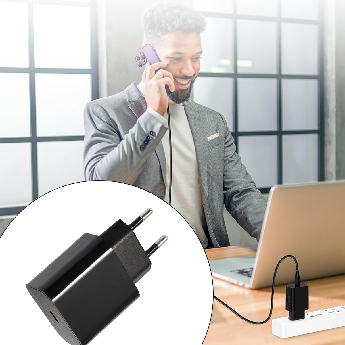 Ein Mann im Anzug telefoniert mit einem Handy, während ein Ladegerät in eine Steckdose in der Nähe eines Laptops eingesteckt ist.
