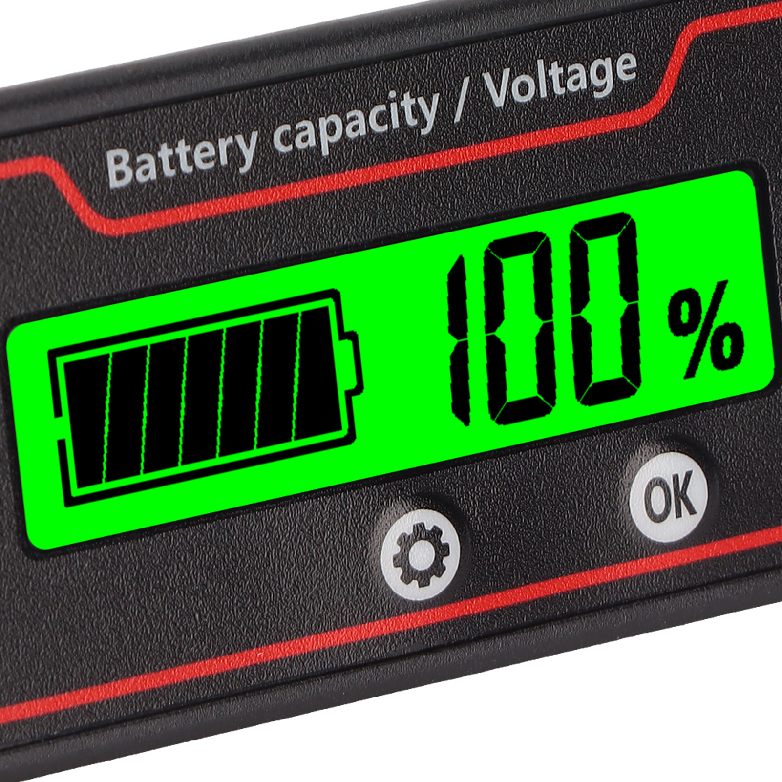 Nahaufnahme eines schwarzen und roten Batteriekapazitäts-/Spannungsmessers, der 100 % Batterie mit OK- und Einstelltasten anzeigt.