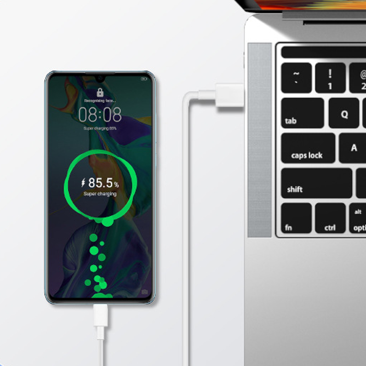 Ein aufladendes Telefon mit der Anzeige „85,5 % Super Charging“ ist mit einem weißen USB-C-Kabel an einen Laptop angeschlossen.