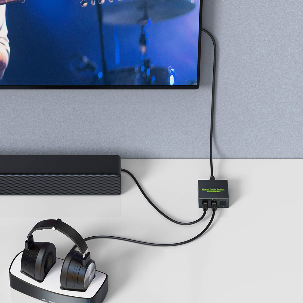 Eine Soundbar und Kopfhörer sind an einen digitalen Audio-Splitter angeschlossen, der mit einem Fernseher verbunden ist.
